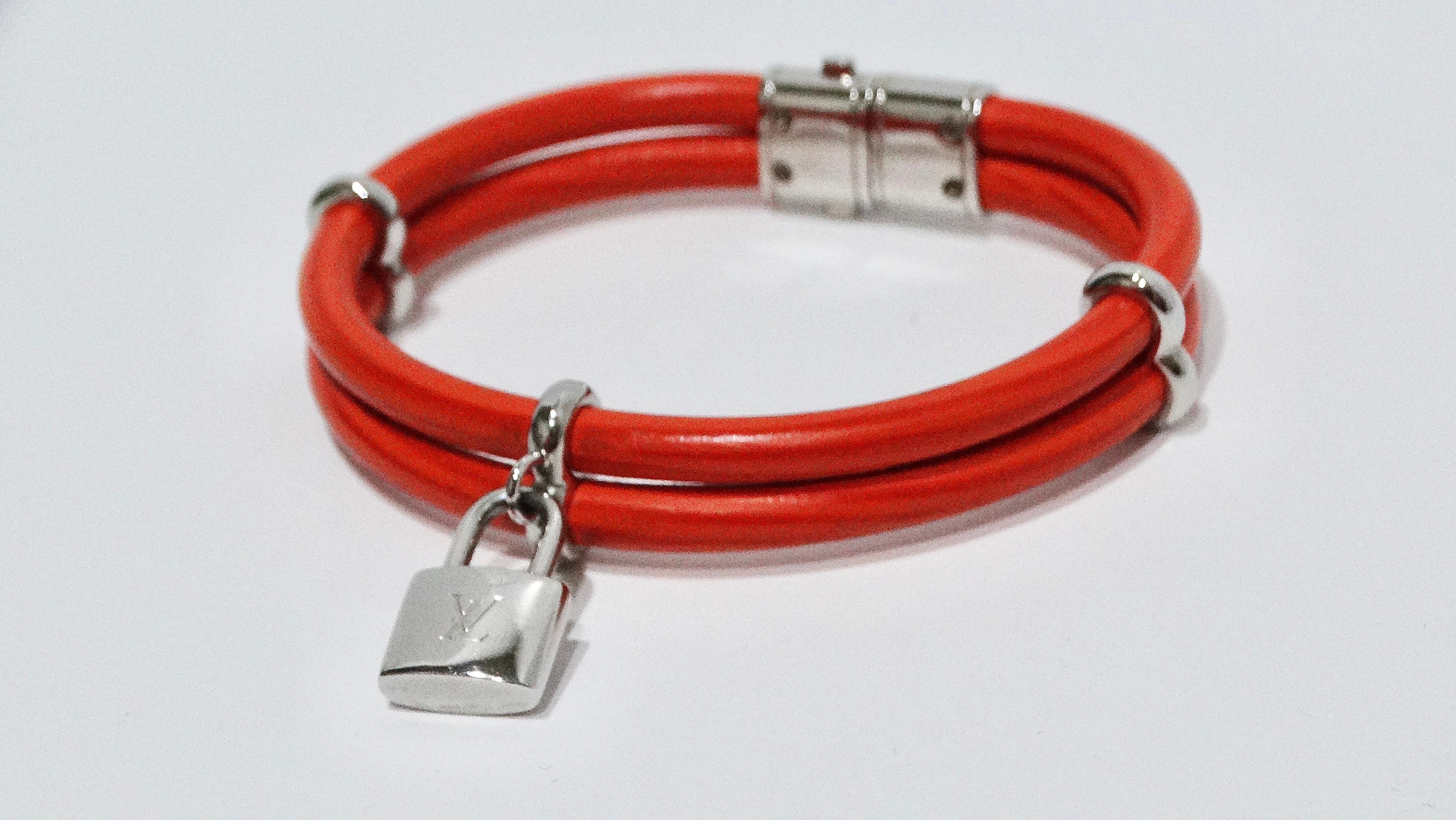 Le bracelet double en cuir Louis Vuitton, de couleur orange vif, est un accessoire unique et accrocheur qui ajoute une touche de couleur amusante à n'importe quelle tenue. Doté de ferrures en argent et d'un charme de serrure LV, ce bracelet allie