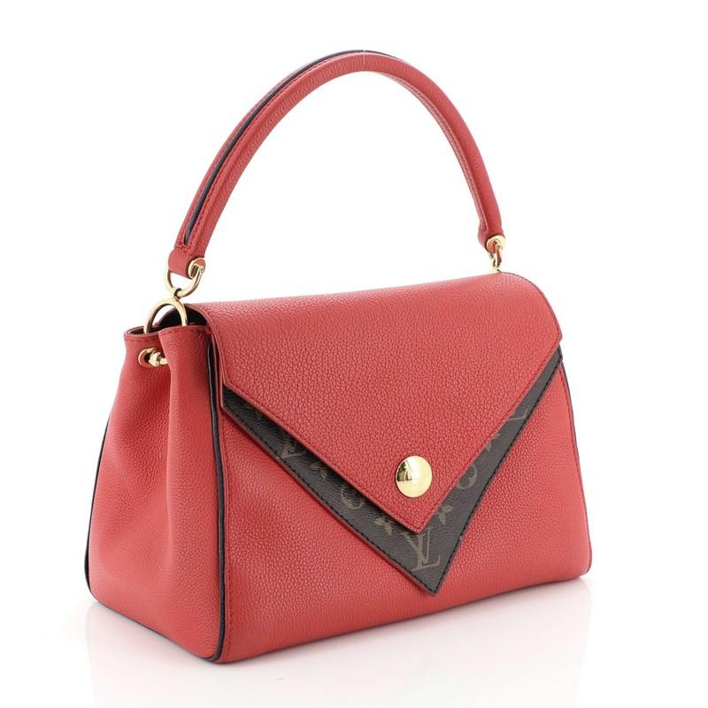 This Louis Vuitton Double V Handbag Calfskin and Monogram Canvas, crafted in red calfskin leather and monogram coated canvas, features a rolled top handle, exterior back pocket, protective base studs, and gold-tone hardware. Its magnetic snap button