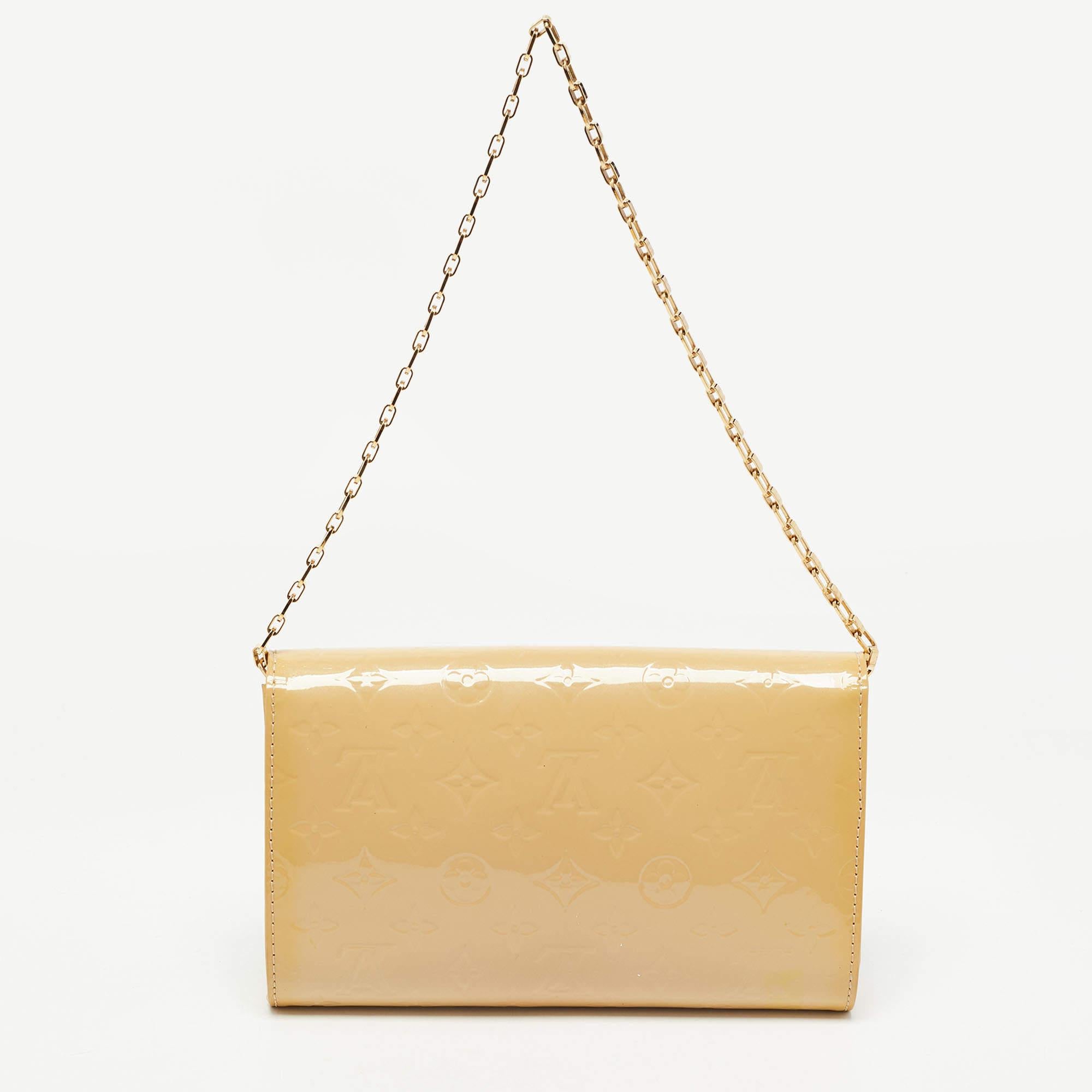 Own this gorgeous Ana clutch by Louis Vuitton today and flaunt it wherever you go. The exterior of the clutch has been crafted from Monogram Vernis, and the flap has a gold-tone metal frame that opens to a compartment for you to neatly arrange your