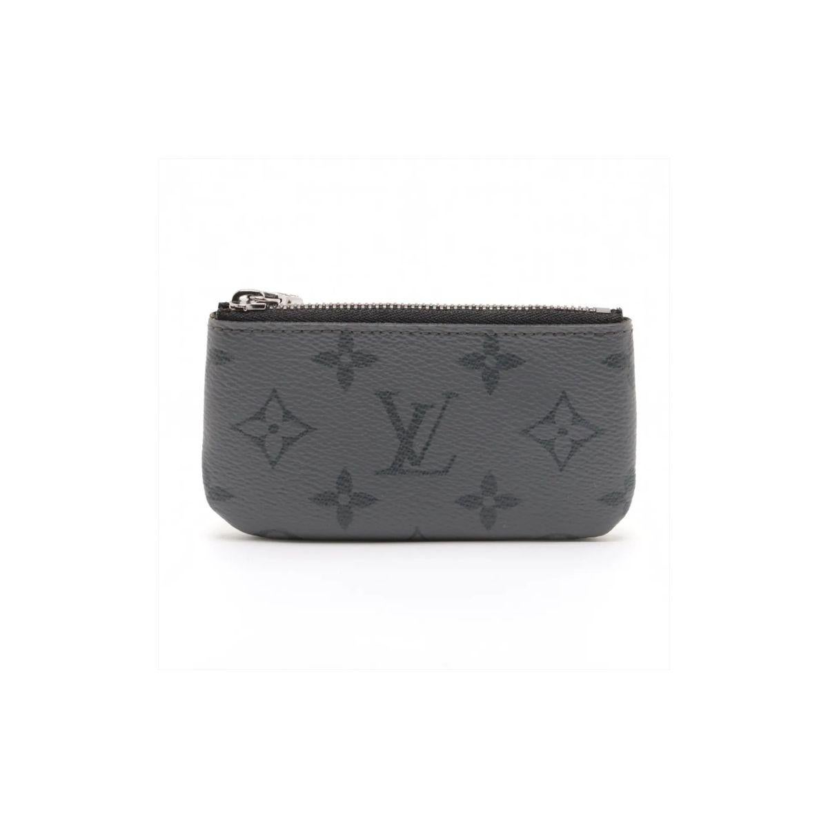 Le porte-monnaie Eclipse Pochette de Louis Vuitton, de couleur grise, est un accessoire élégant et raffiné qui allie parfaitement design minimaliste et élégance fonctionnelle. Confectionné dans la remarquable toile Eclipse Monogram, il arbore un