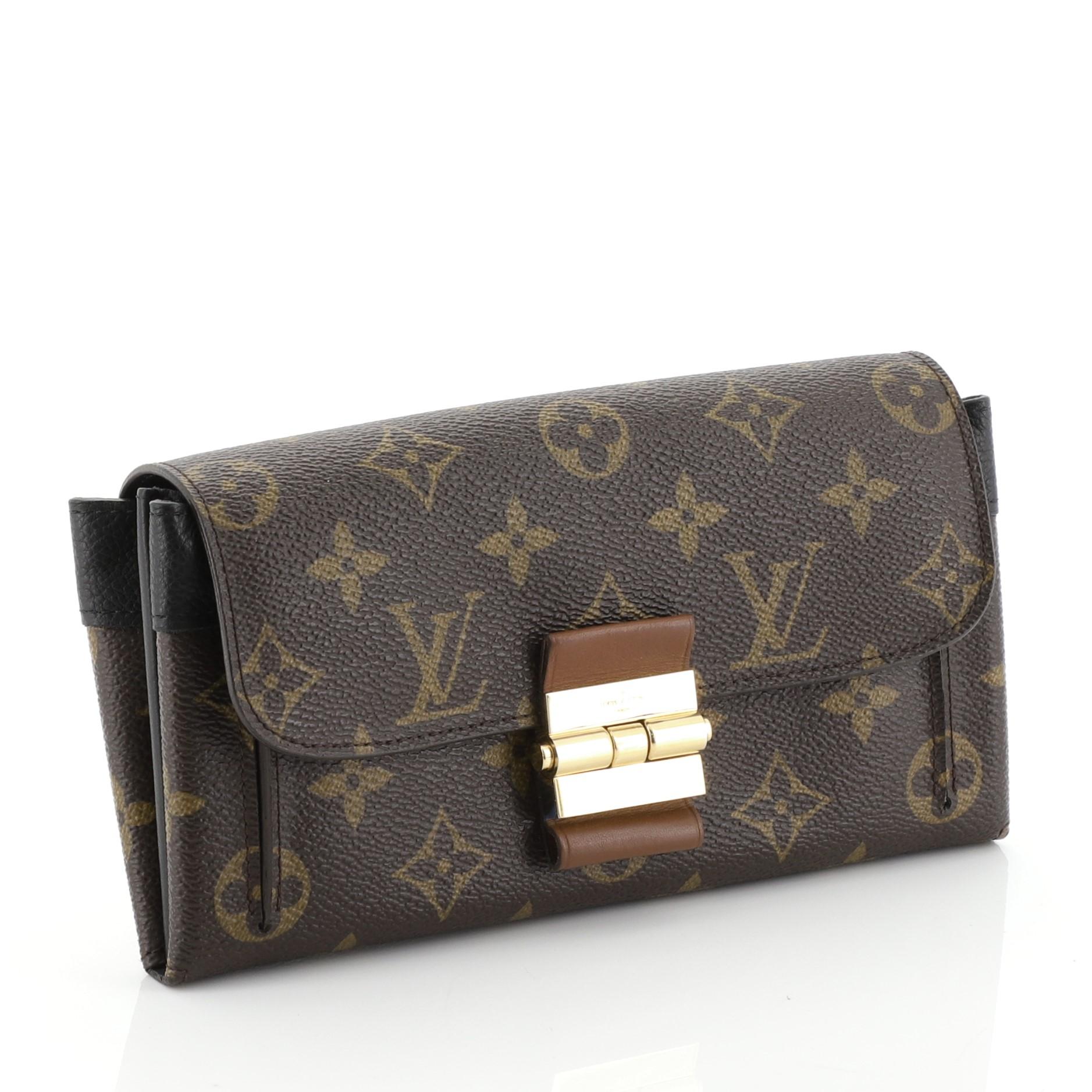 This Louis Vuitton Elysee Wallet Monogram Canvas and Leather, crafted in brown monogram coated canvas and leather, features slip pocket under flap and gold-tone hardware. Its flap opens to a brown monogram coated canvas and black leather interior