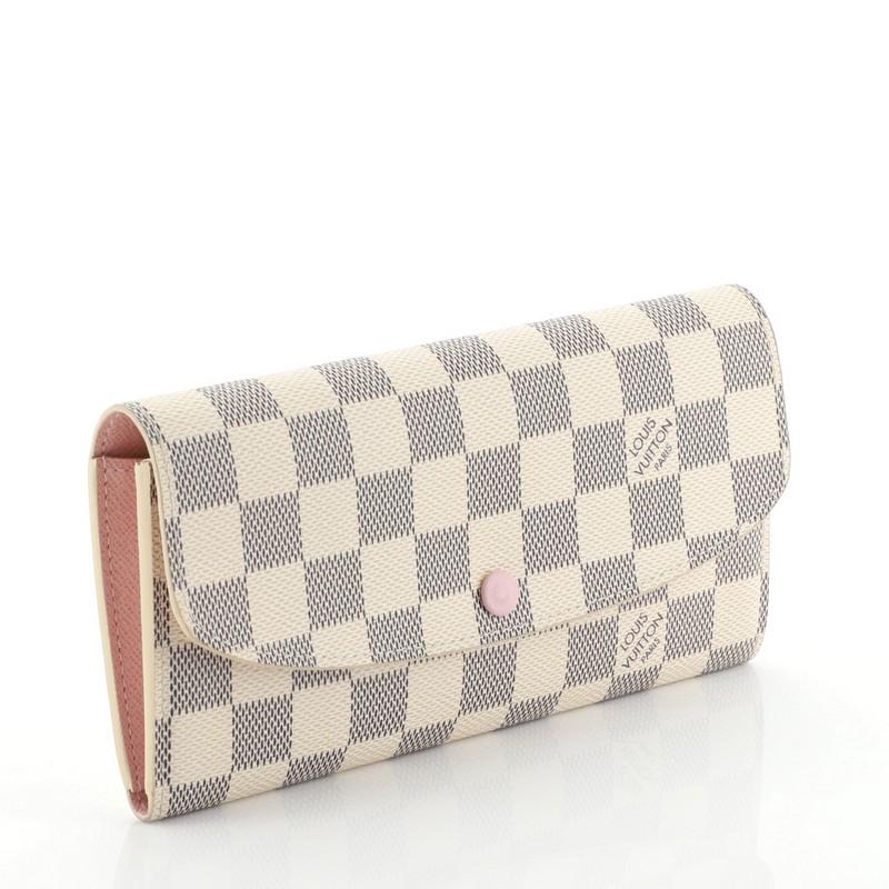 This Louis Vuitton Emilie Wallet Damier, crafted from damier azur coated canvas, features gold-tone hardware. Its frontal flap with snap button closure opens to a pink leather interior with zip and slip pockets. Authenticity code reads: TA4127.