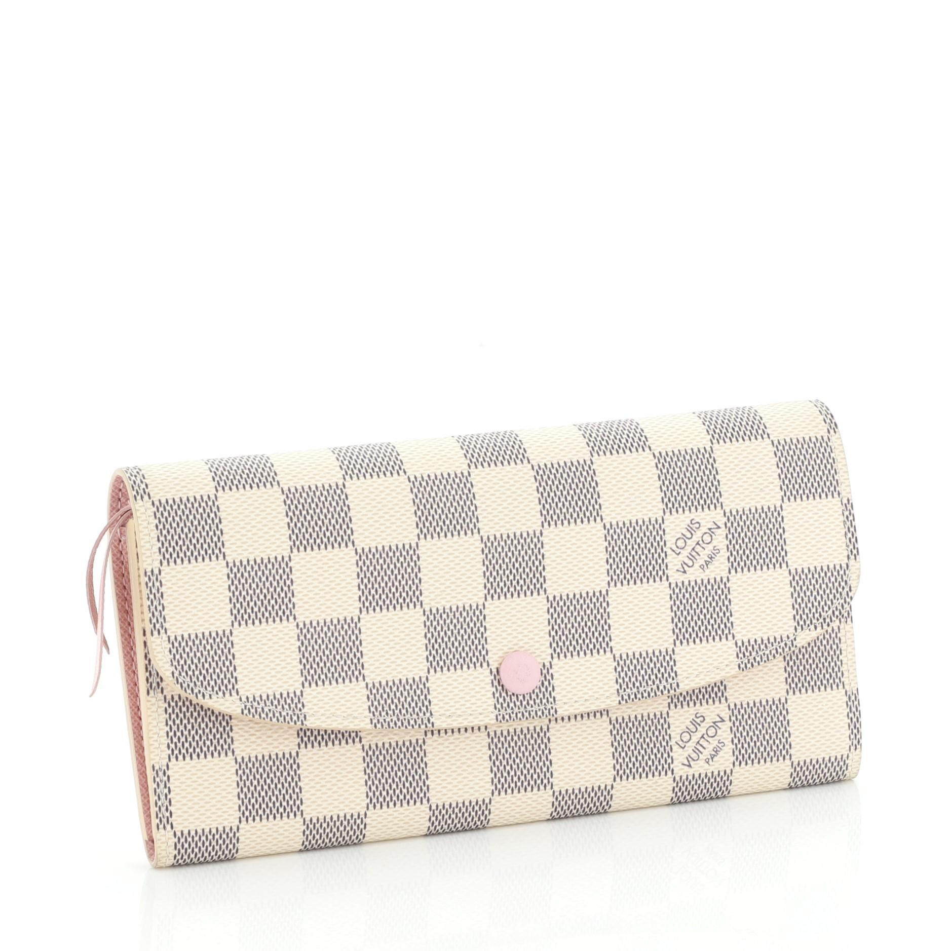 This Louis Vuitton Emilie Wallet Damier, crafted from damier azur coated canvas, features gold-tone hardware. Its frontal flap with snap button closure opens to a pink leather interior with zip and slip pockets. Authenticity code reads: