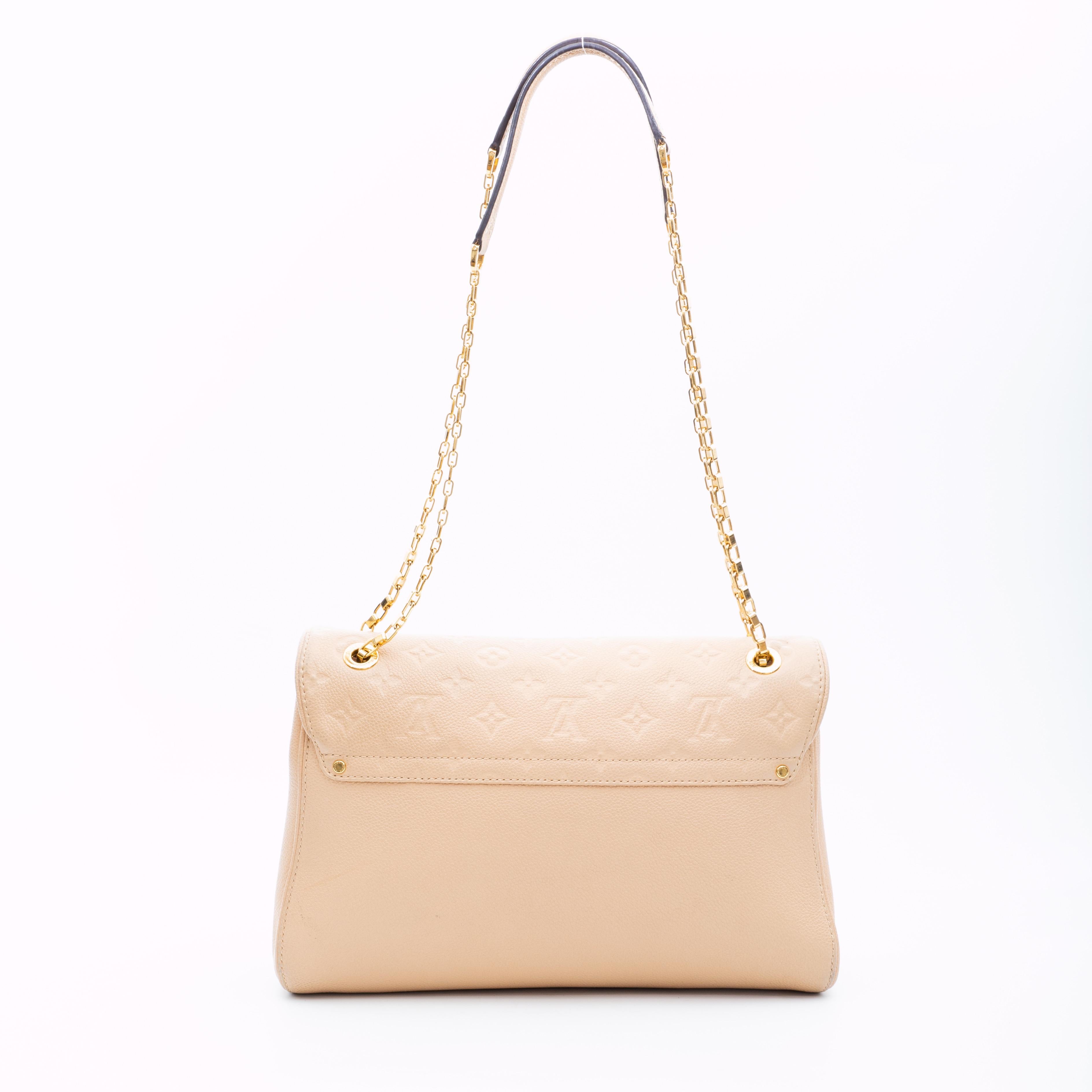 This bag is made from a supple grained cowhide called Empreinte leather with Louis Vuitton's signature monogram pattern embossed. The bag features a beige exterior, light gold tone hardware, a chain link shoulder strap for comfortable carry,