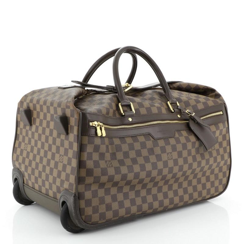 This Louis Vuitton Eole Bag Damier 50, crafted in damier ebene coated canvas, features dual rolled leather handles, sturdy rollers, leather trim, exterior zip pocket and gold-tone hardware. Its zip closure opens to a brown fabric interior with slip