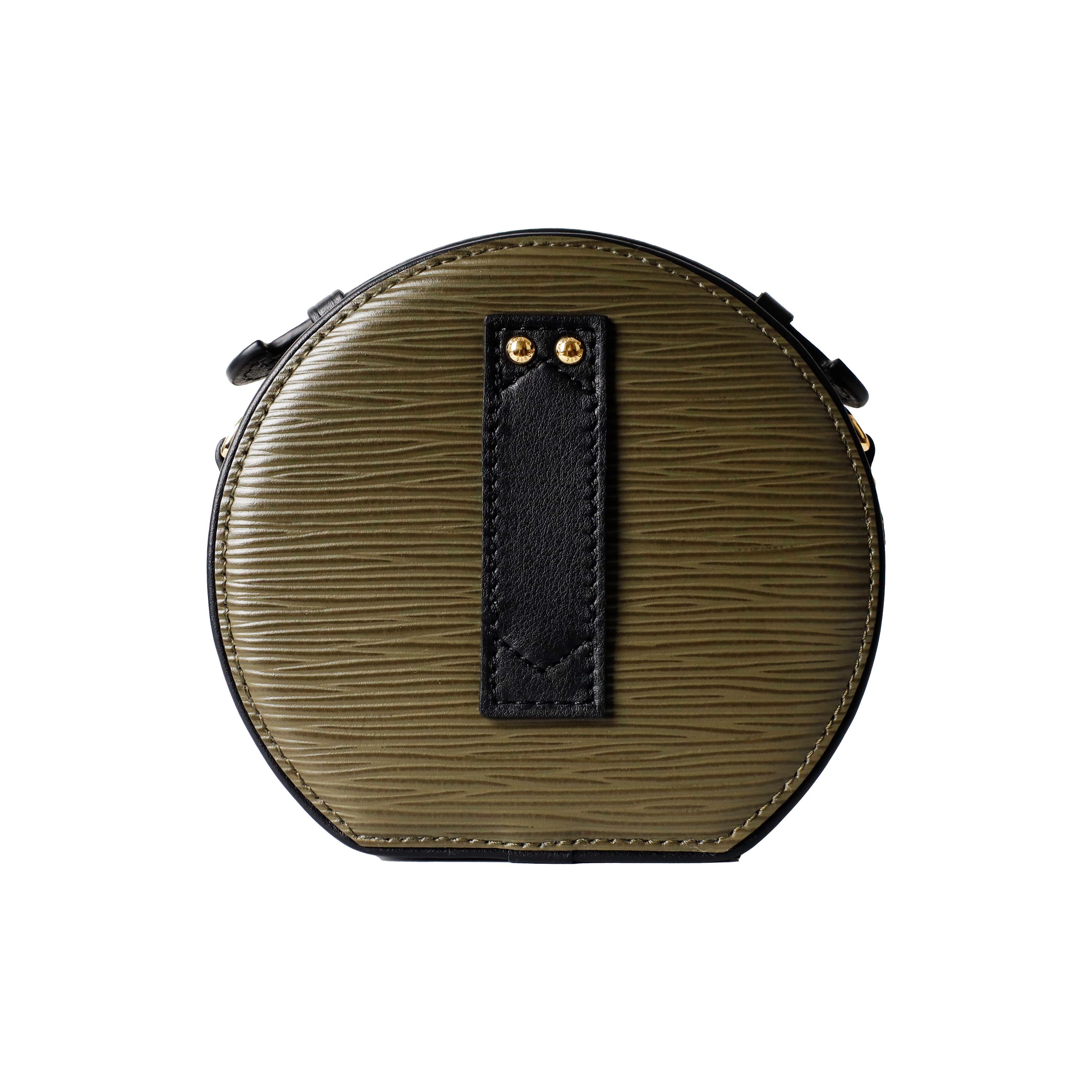 The Louis Vuitton Epi Mini Boite Chapeau bag is crafted from textured green epi leather, with an elegant black leather handle and adjustable shoulder strap. The polished brass hardware and partitioned interior make it both stylish and functional.