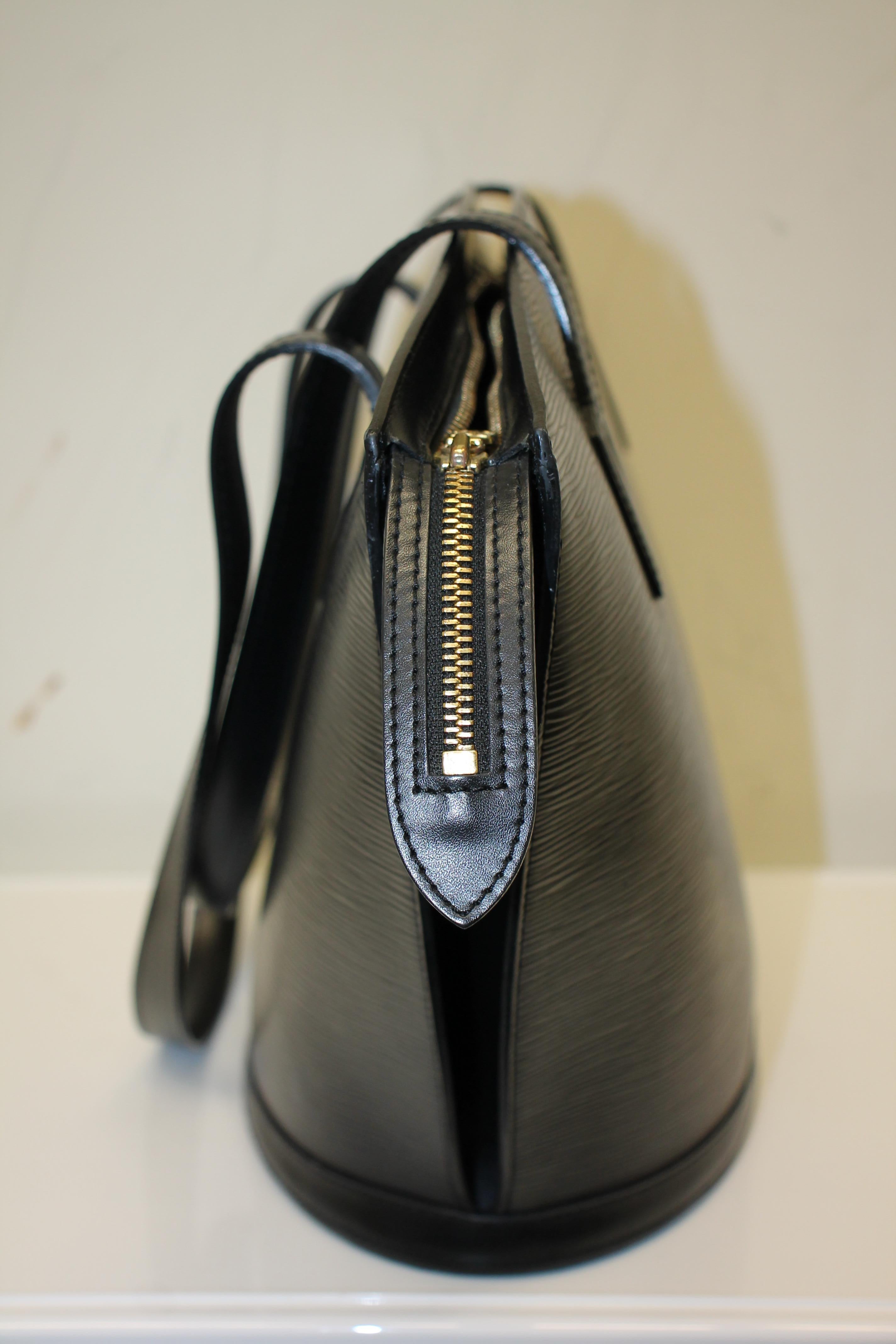 Black Epi leather. Brass hardware. Zip closure at top. Dual flat shoulder straps. Charcoal Alcantara lining. One interior zippered pocket. Estimated Retail: $1,350