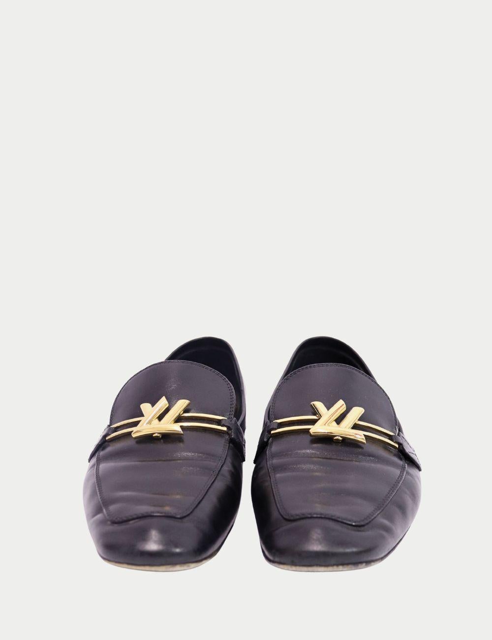 Adéntrate en la elegancia atemporal con estos mocasines Louis Vuitton de piel negra, un refinado básico para el armario moderno. Fabricados en piel negra flexible, estos mocasines llevan los icónicos herrajes dorados de LV en el empeine, para un