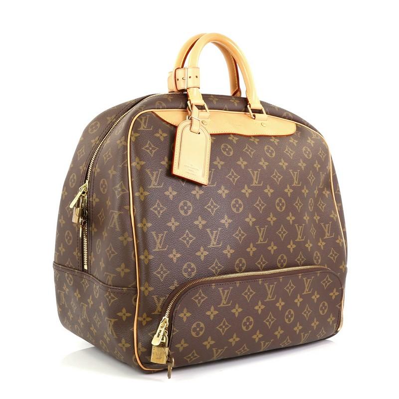 This Louis Vuitton Evasion Travel Bag Monogram Canvas MM, crafted in brown monogram coated canvas, features dual rolled leather handles, front bottom zip compartment, and gold-tone hardware. Its two-way zip closure opens to a neutral canvas interior