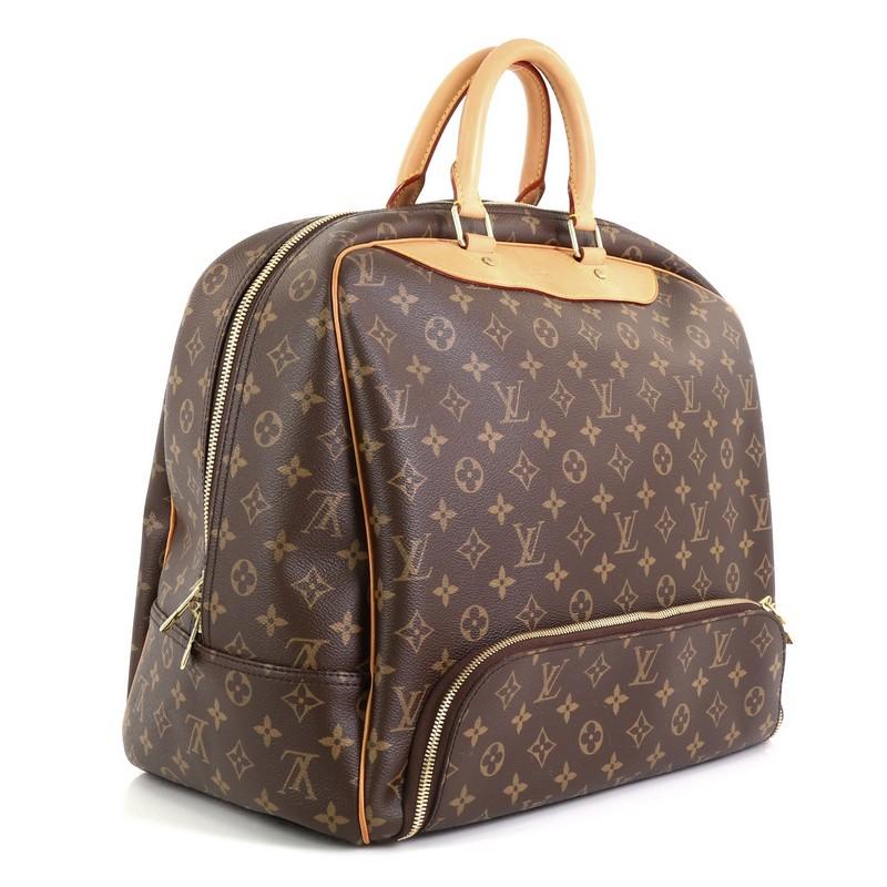 This Louis Vuitton Evasion Travel Bag Monogram Canvas MM, crafted in brown monogram coated canvas, features dual rolled leather handles, front bottom zip compartment, and gold-tone hardware. Its two-way zip closure opens to a neutral canvas interior