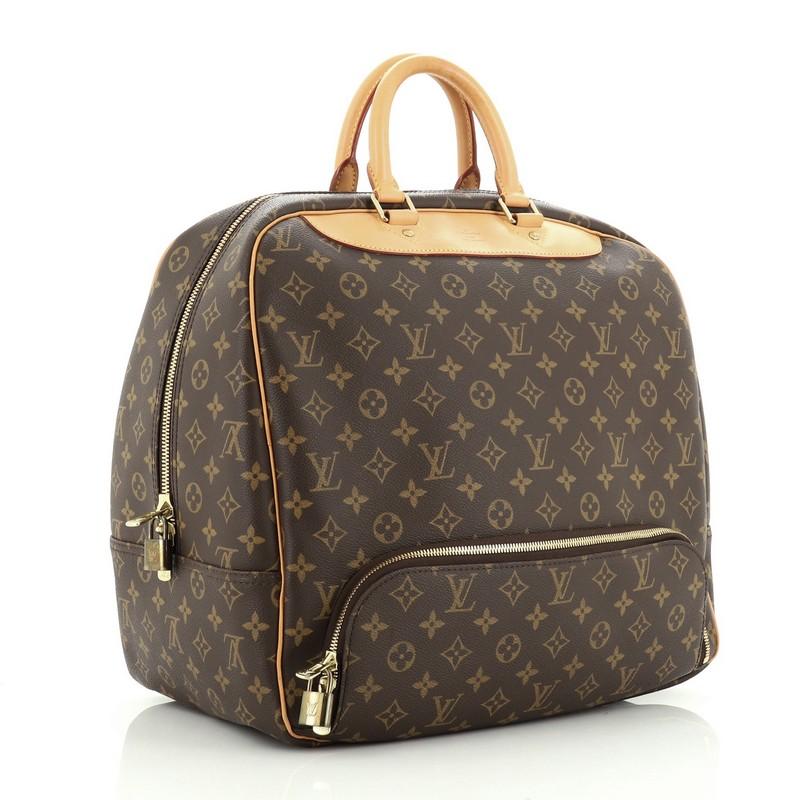 This Louis Vuitton Evasion Travel Bag Monogram Canvas MM, crafted in brown monogram coated canvas, features dual rolled leather handles, front bottom zip compartment, and gold-tone hardware. Its two-way zip closure opens to a neutral canvas interior