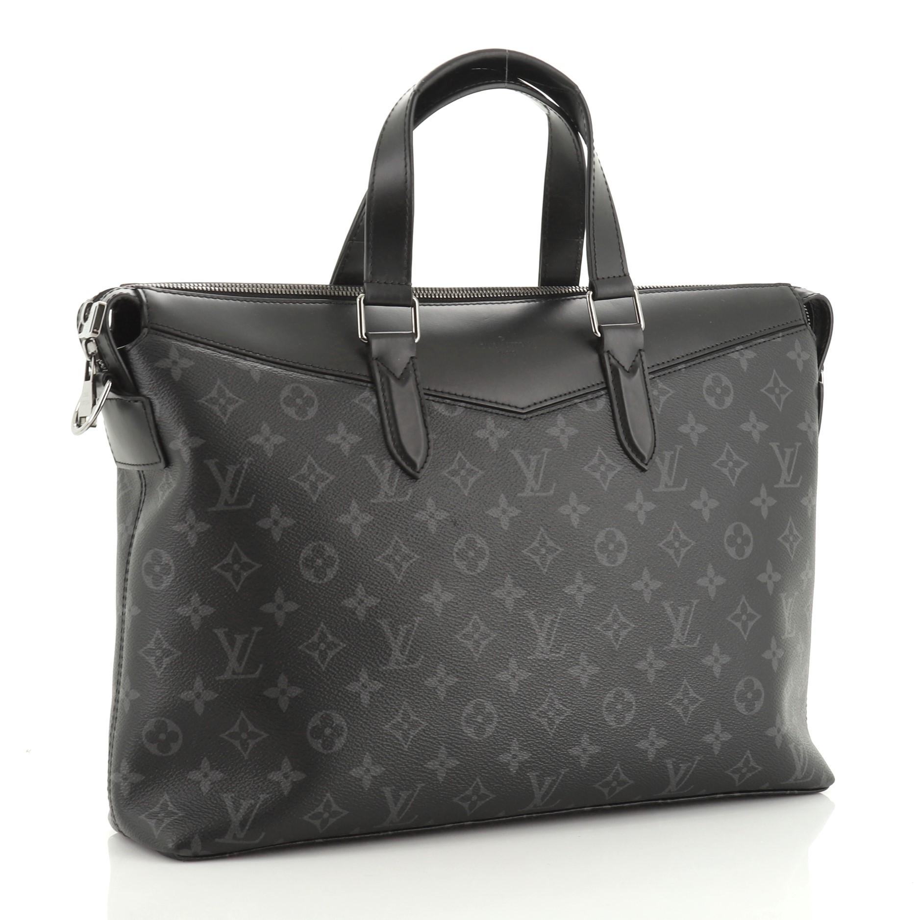 This Louis Vuitton Explorer Briefcase Monogram Eclipse Canvas, crafted in black monogram eclipse coated canvas, features dual flat leather handles, adjustable shoulder strap, leather trim, and gunmetal-tone hardware. Its zip closure opens to a black