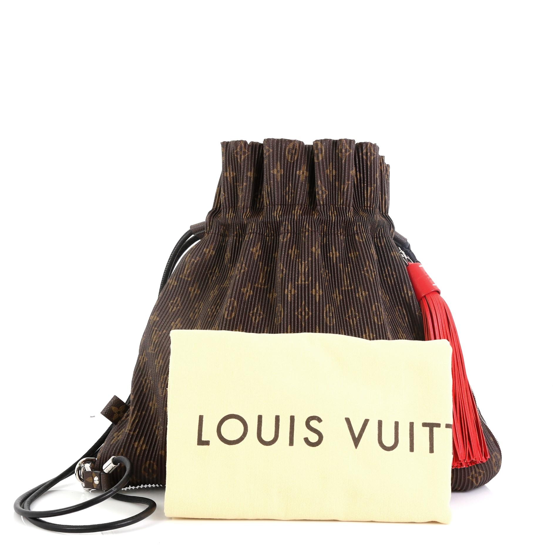 This Louis Vuitton Explorer Shoulder Bag Pleated Monogram Canvas MM, crafted in brown pleated monogram canvas, features a leather shoulder strap, exterior side zip pocket with tassel charm, and silver-tone hardware. Its drawstring closure opens to a