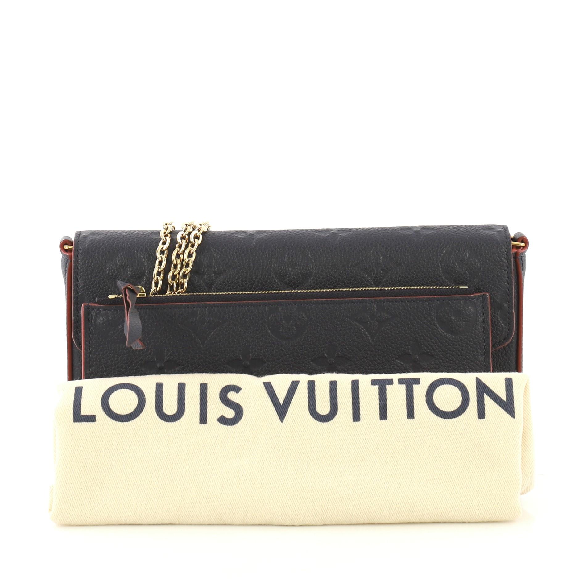 This Louis Vuitton Felicie Pochette Monogram Empreinte Leather, crafted from navy monogram empreinte leather, features a detachable chain strap and gold-tone hardware. Its press stud closure opens to a red fabric interior with slip pocket.