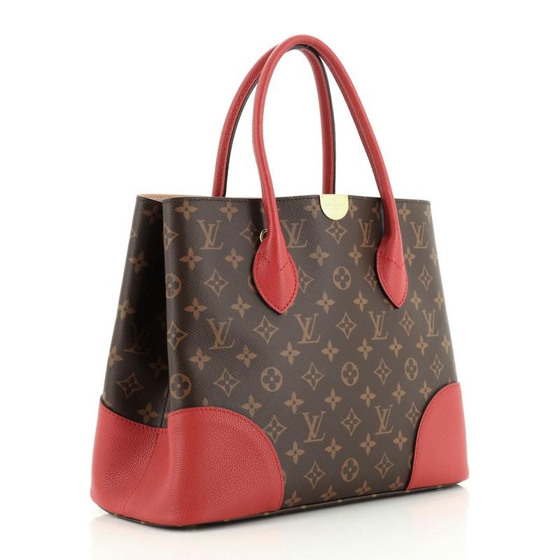 This Louis Vuitton Flandrin Handbag Monogram Canvas, crafted from brown monogram coated canvas and red leather, features dual rolled leather handles and gold-tone hardware. It opens to a neutral microfiber interior with a center zip compartment.