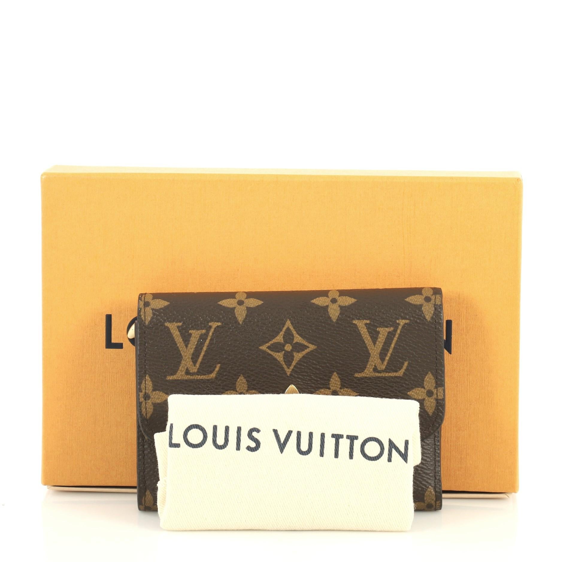 This Louis Vuitton Flower Compact Wallet Monogram Canvas, crafted in brown monogram coated canvas, features a monogram flower with padlock and gold-tone hardware. Its flap top with snap closure opens to a black leather interior with multiple card