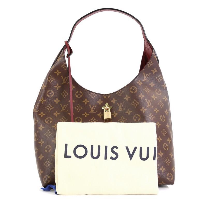 This Louis Vuitton Flower Hobo Monogram Canvas, crafted from brown monogram coated canvas, features looping leather top handle, frontal flower lock and gold-tone hardware. It opens to a purple microfiber interior with zip and slip pockets.