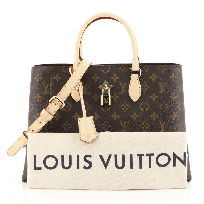 This Louis Vuitton Flower Tote Monogram Canvas, crafted in brown monogram coated canvas, features dual rolled leather handles, monogram flower padlock, and gold-tone hardware. It opens to a purple microfiber interior with a center zip compartment