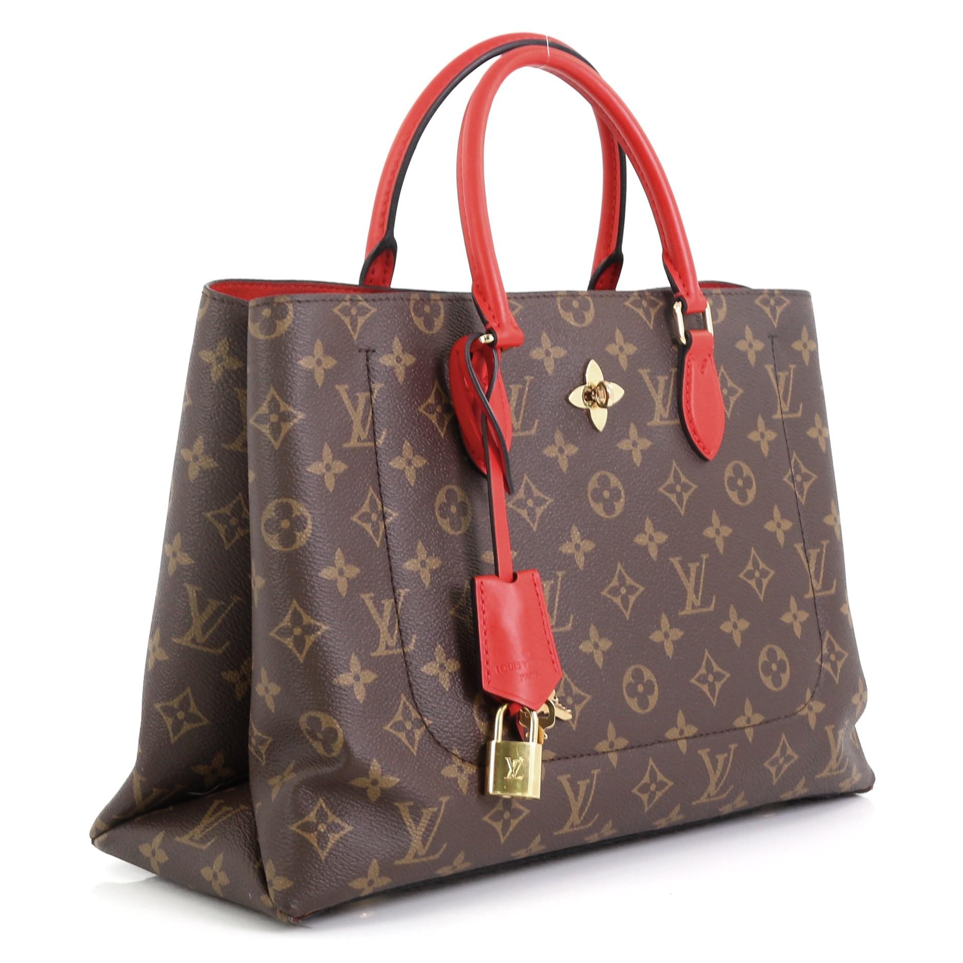 This Louis Vuitton Flower Tote Monogram Canvas, crafted in brown monogram coated canvas, features dual rolled leather handles, monogram flower padlock, and gold-tone hardware. It opens to a red microfiber interior with a center zip compartment and