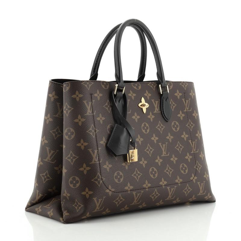 This Louis Vuitton Flower Tote Monogram Canvas, crafted in brown monogram coated canvas, features dual rolled leather handles, monogram flower padlock, and gold-tone hardware. It opens to a black microfiber interior with a center zip compartment and