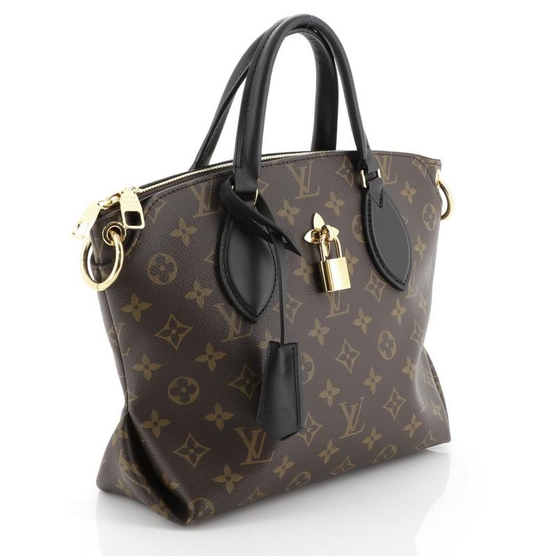 This Louis Vuitton Flower Zipped Tote Monogram Canvas BB, crafted in brown monogram coated canvas, features dual leather handles, turn lock with fleur detail, and gold-tone hardware. It opens to a partitioned black microfiber interior with flat