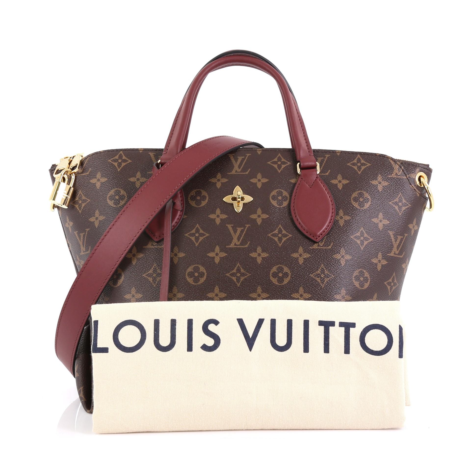 This Louis Vuitton Flower Zipped Tote Monogram Canvas MM, crafted in brown monogram coated canvas, features dual leather handles, turn lock with fleur detail, and gold-tone hardware. It opens to a partitioned burgundy microfiber interior with flat
