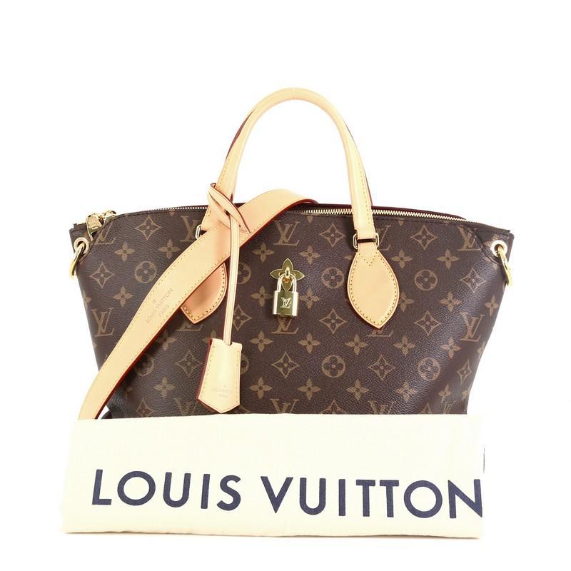 This Louis Vuitton Flower Zipped Tote Monogram Canvas MM, crafted in brown monogram coated canvas, features dual leather handles, turn lock with fleur detail, and gold-tone hardware. It opens to a partitioned purple microfiber interior with flat