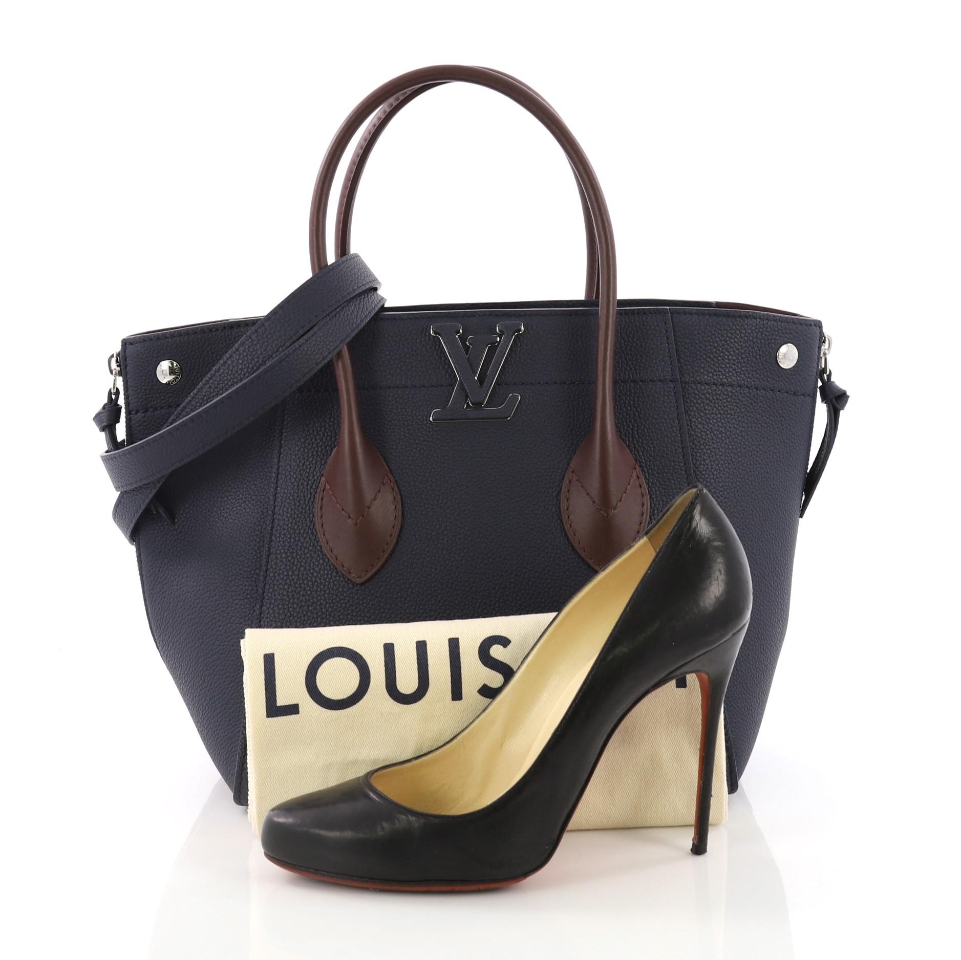 This Louis Vuitton Freedom Handbag Calfskin, crafted in blue calfskin leather, features dual rolled leather handles, cut out leather LV logo on front, side zippers, and silver-tone hardware. Its zip closure opens to a purple microfiber interior with