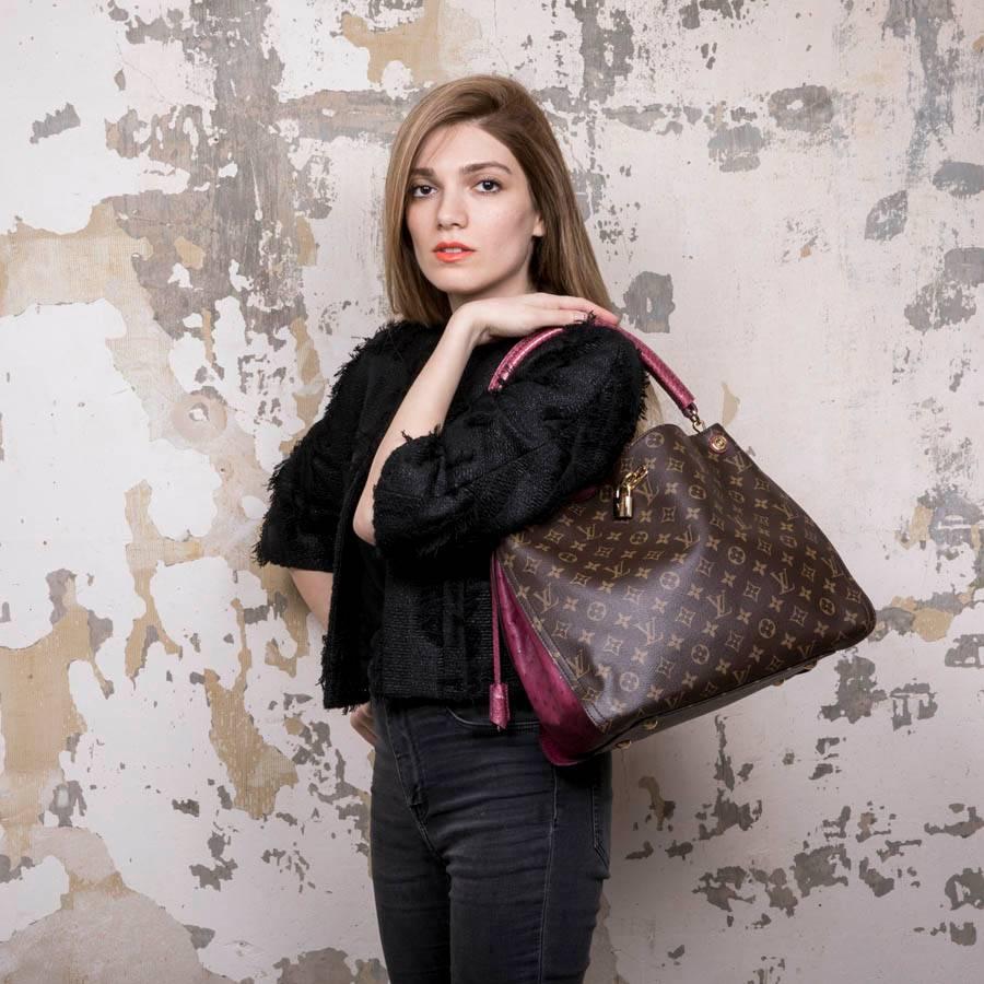 Louis Vuitton 'Gaia' bag in monogram canvas, ostrich and lizard leather. Palladium gold metal hardware Hand carried with a pink lizard handle. Ostrich patch on each side of the bag. The interior is in alcantara with a patch pocket and a zipper