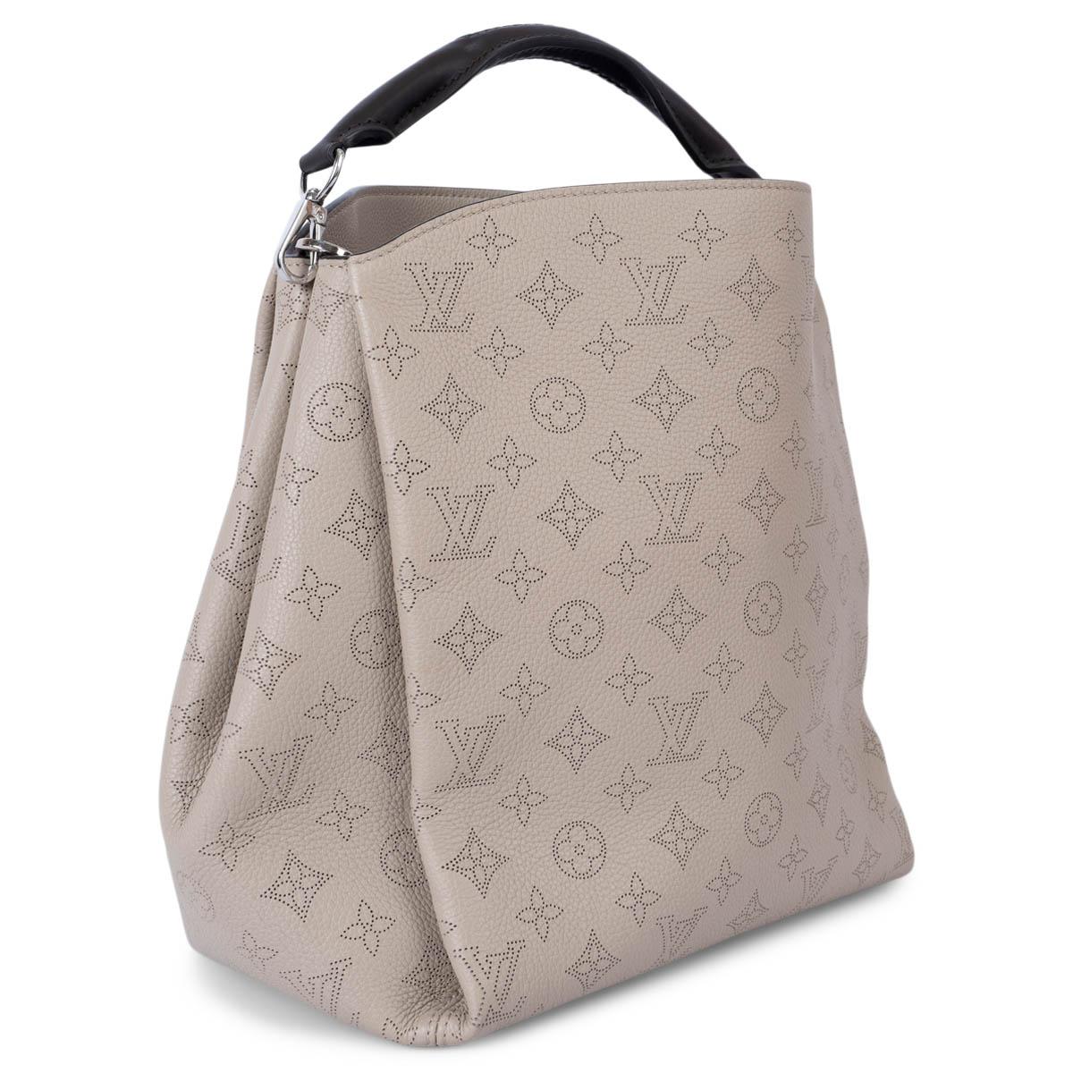 100% authentic Louis Vuitton Babylone PM hobo monogram in galet taupe Mahina leather. The design features a espresso brown rolled and braided leather handle and is lined in dark brown alcantara with one zipper pocket against the back and two open