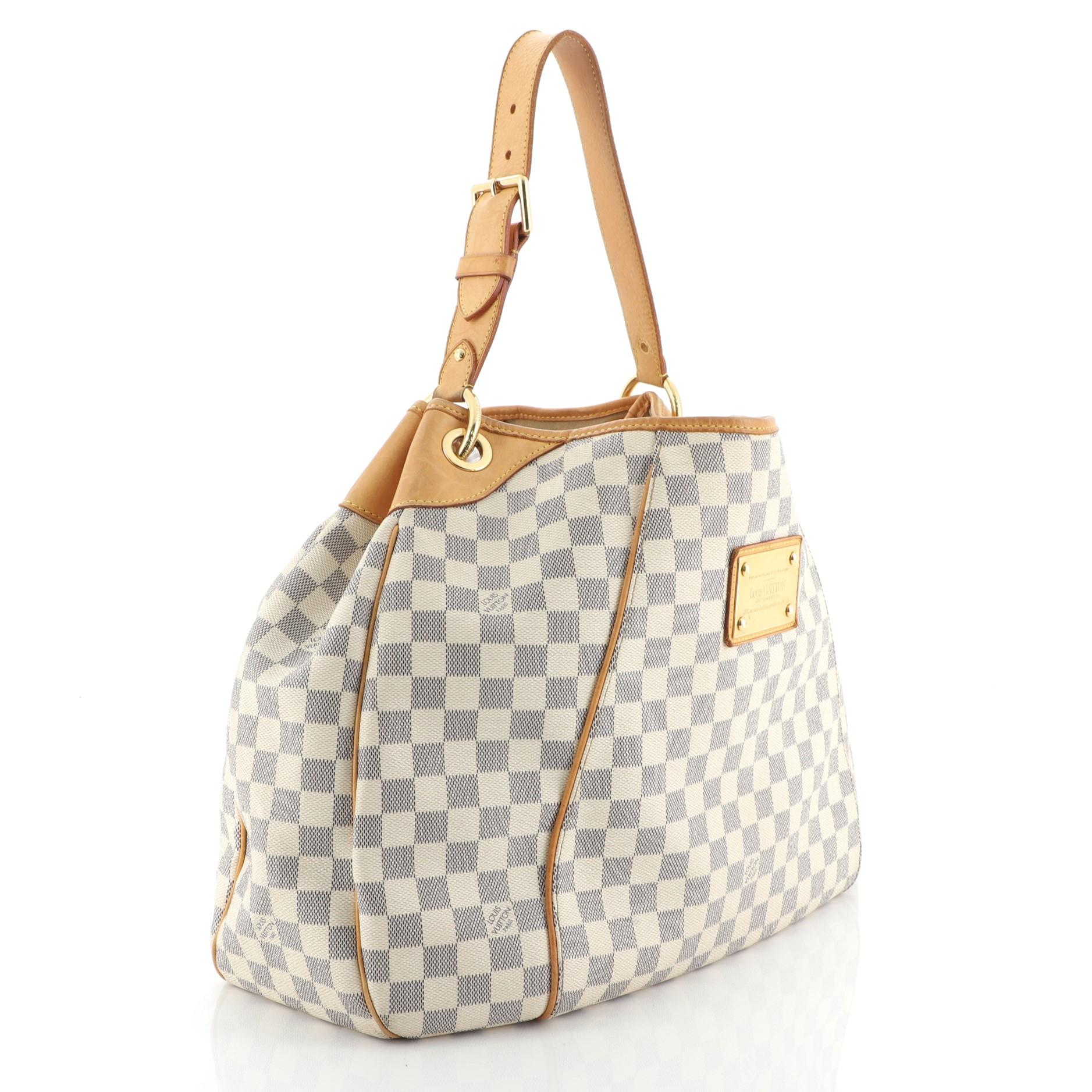 This Louis Vuitton Galliera Handbag Damier GM, crafted in damier azur coated canvas, features an adjustable shoulder strap, cowhide leather trim, and gold-tone hardware. Its magnetic snap closure opens to a neutral microfiber interior with snap and