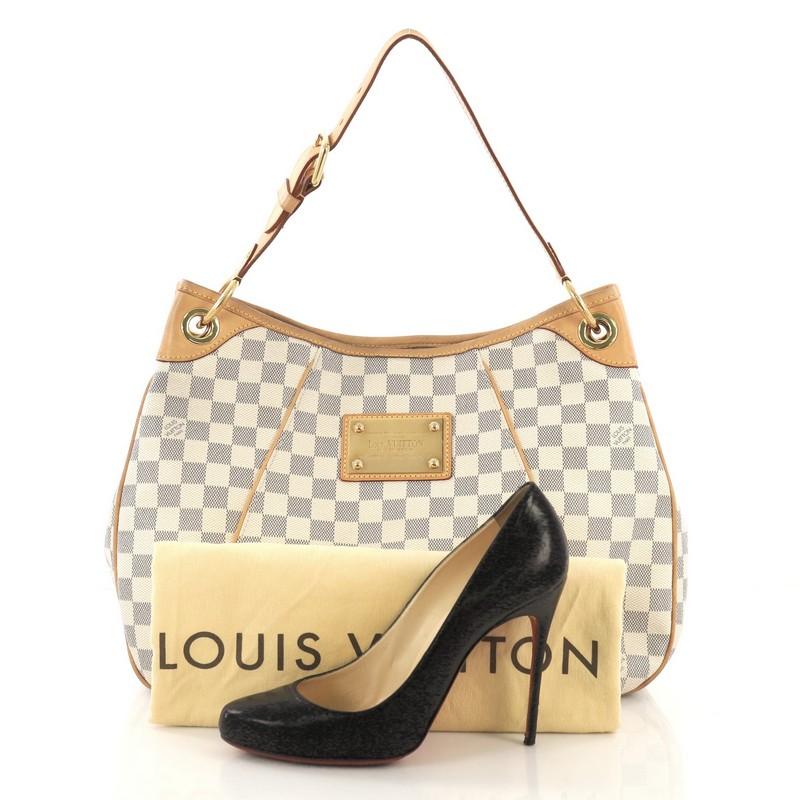 This Louis Vuitton Galliera Handbag Damier PM, crafted from damier azur coated canvas, features an adjustable shoulder strap, leather trim, metal logo plate, and gold-tone hardware. Its magnetic snap closure opens to a beige microfiber interior with