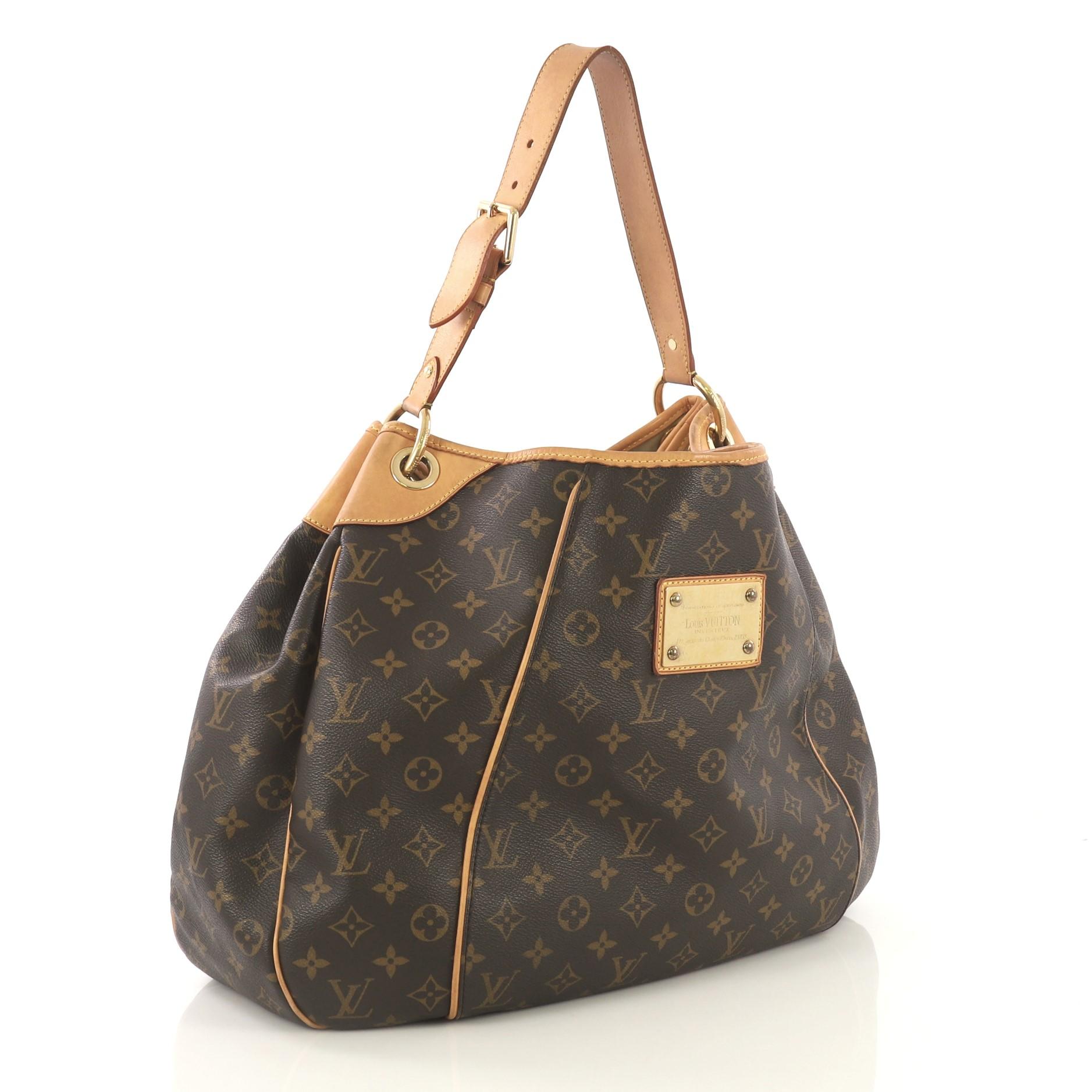 This Louis Vuitton Galliera Handbag Monogram Canvas GM, crafted in brown monogram coated canvas, features an adjustable shoulder strap, cowhide leather trim, and gold-tone hardware. Its magnetic snap closure opens to a neutral microfiber interior