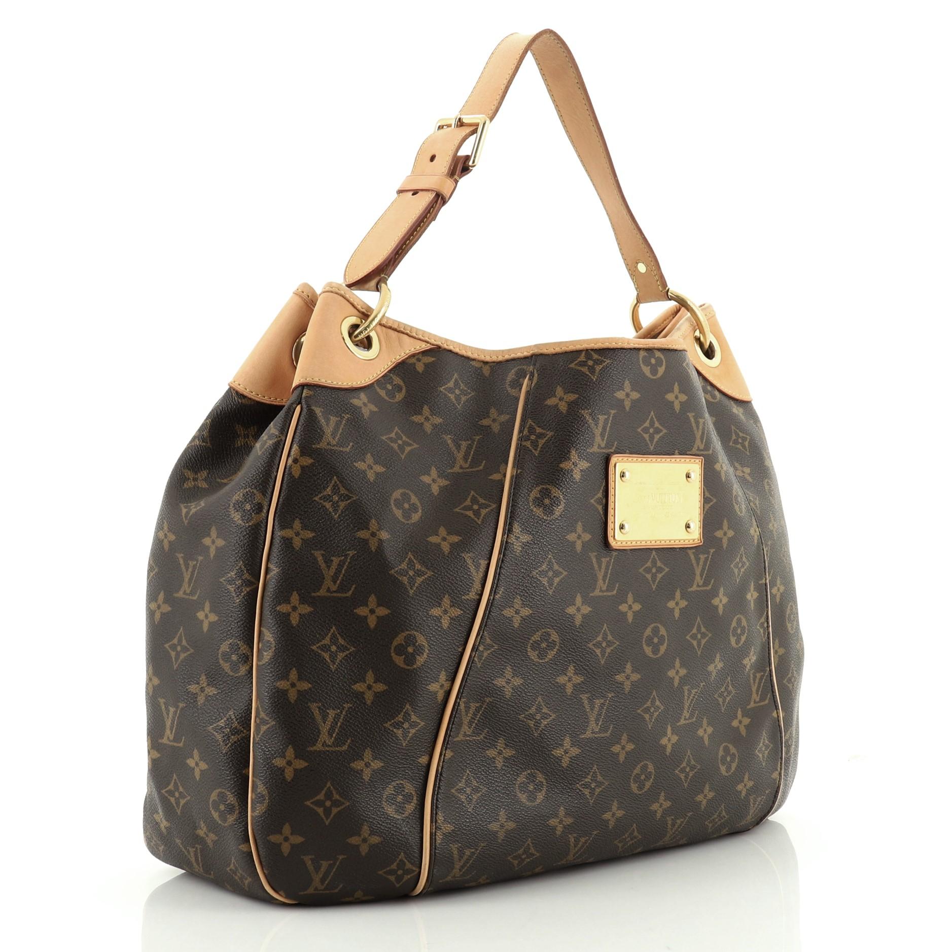 This Louis Vuitton Galliera Handbag Monogram Canvas GM, crafted in brown monogram coated canvas, features an adjustable shoulder strap, cowhide leather trim, and gold-tone hardware. Its magnetic snap closure opens to a neutral microfiber interior