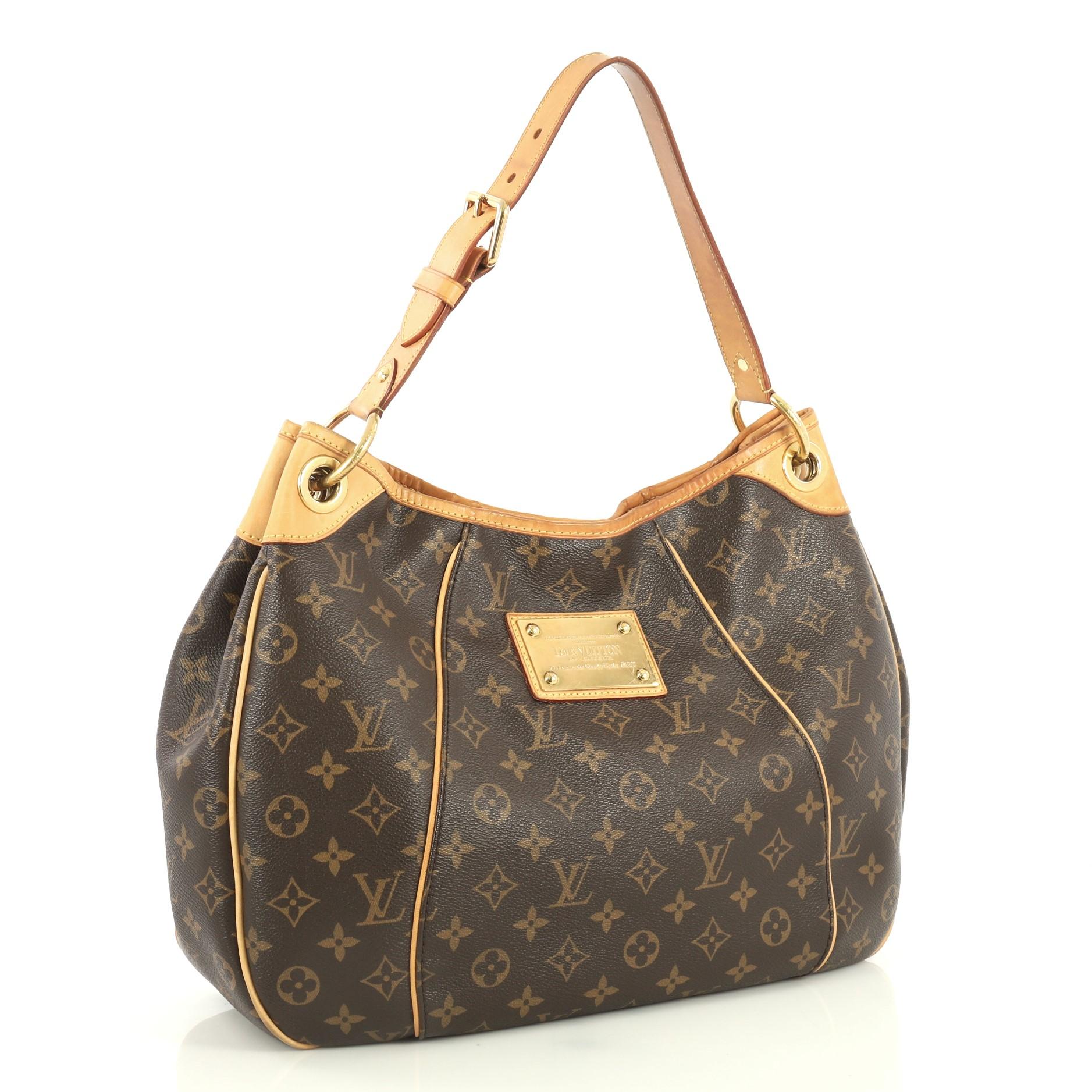 This Louis Vuitton Galliera Handbag Monogram Canvas PM, crafted in brown monogram coated canvas, features an adjustable shoulder strap, cowhide leather trim, and gold-tone hardware. Its magnetic snap closure opens to a neutral microfiber interior
