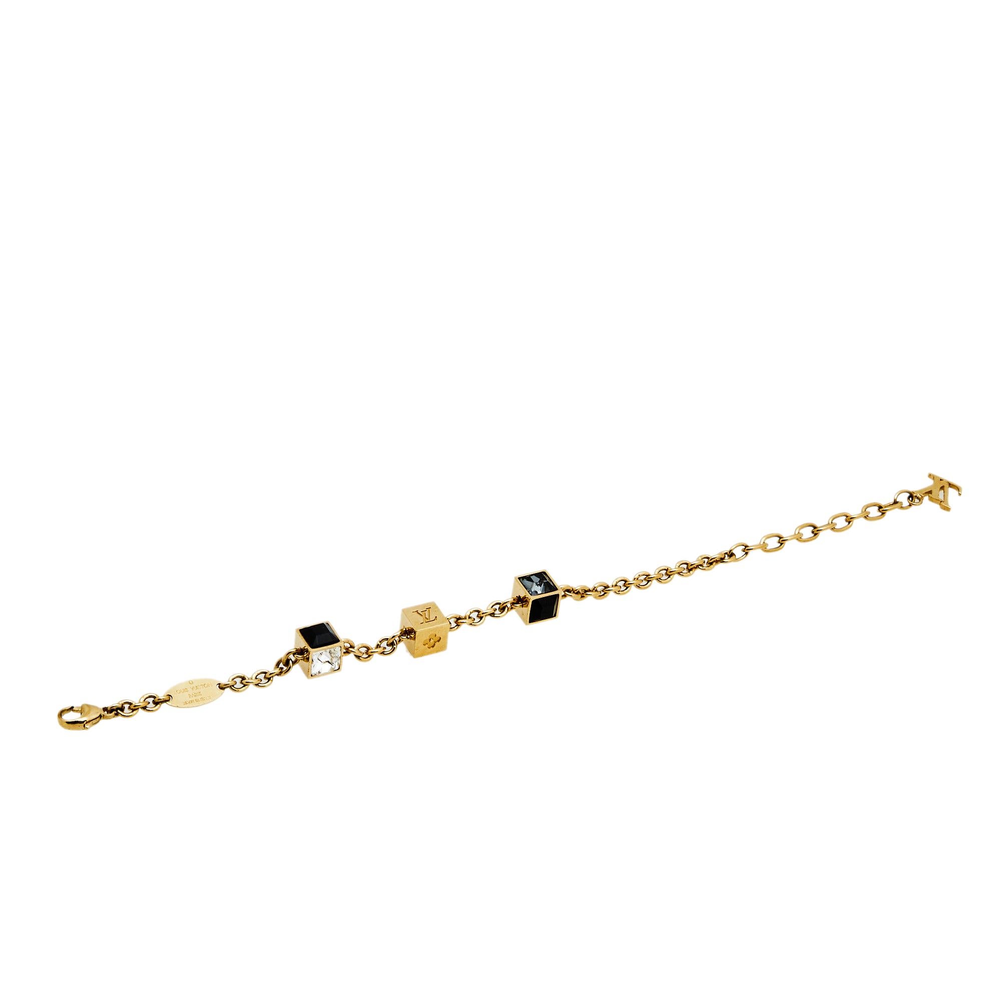 Artfully made from gold-tone metal, this flawless bracelet by Louis Vuitton can be your next prized possession. Featuring a gorgeous set of 3 cubes with monogram engravings and crystals, the design has been finished with the signature LV logo and a