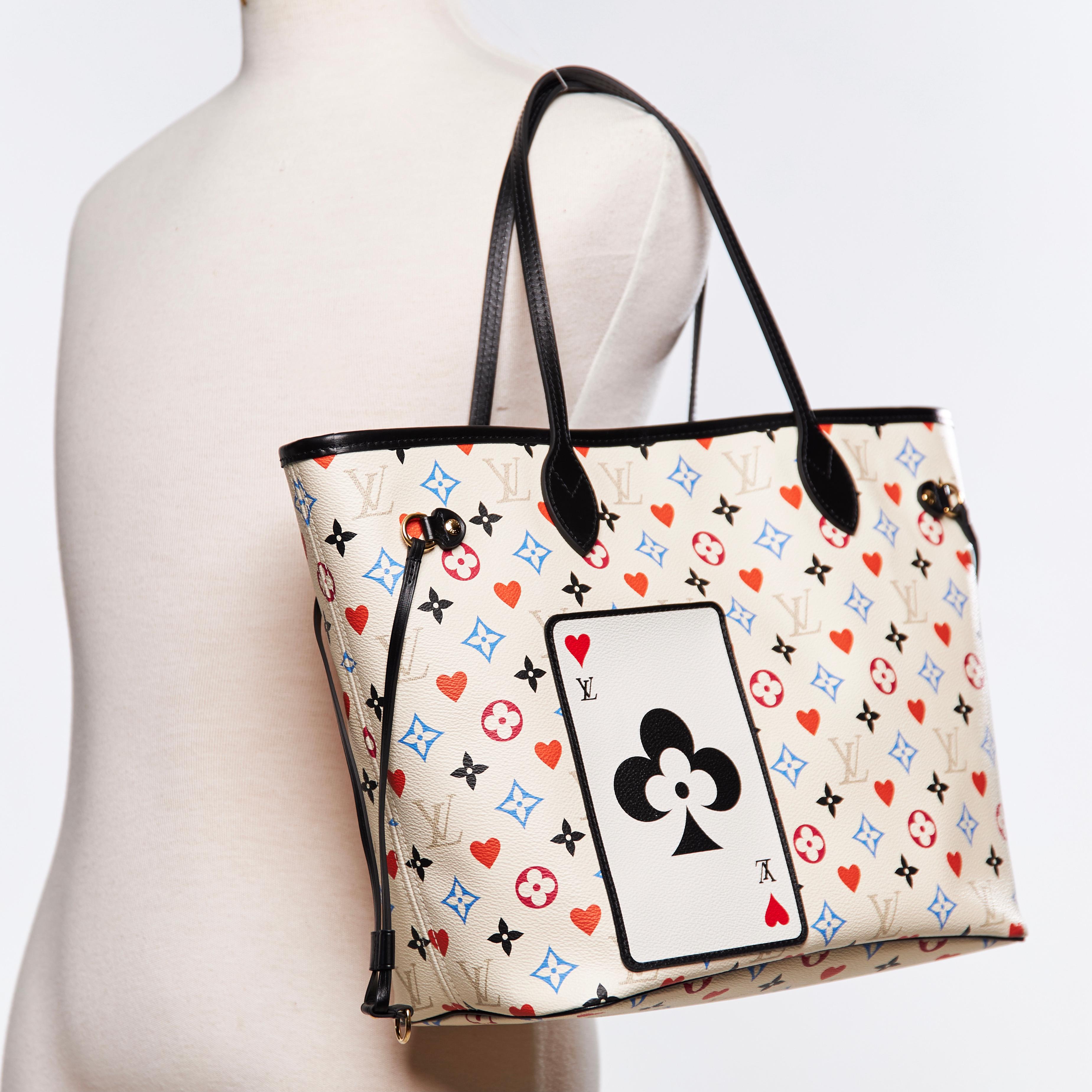 This tote bag is made of Louis Vuitton monogram on coated canvas in white with red hearts and multicolor monograms. The bag features flat black leather top handles, side cinch cords, and polished brass hardware. The top opens to a spacious black