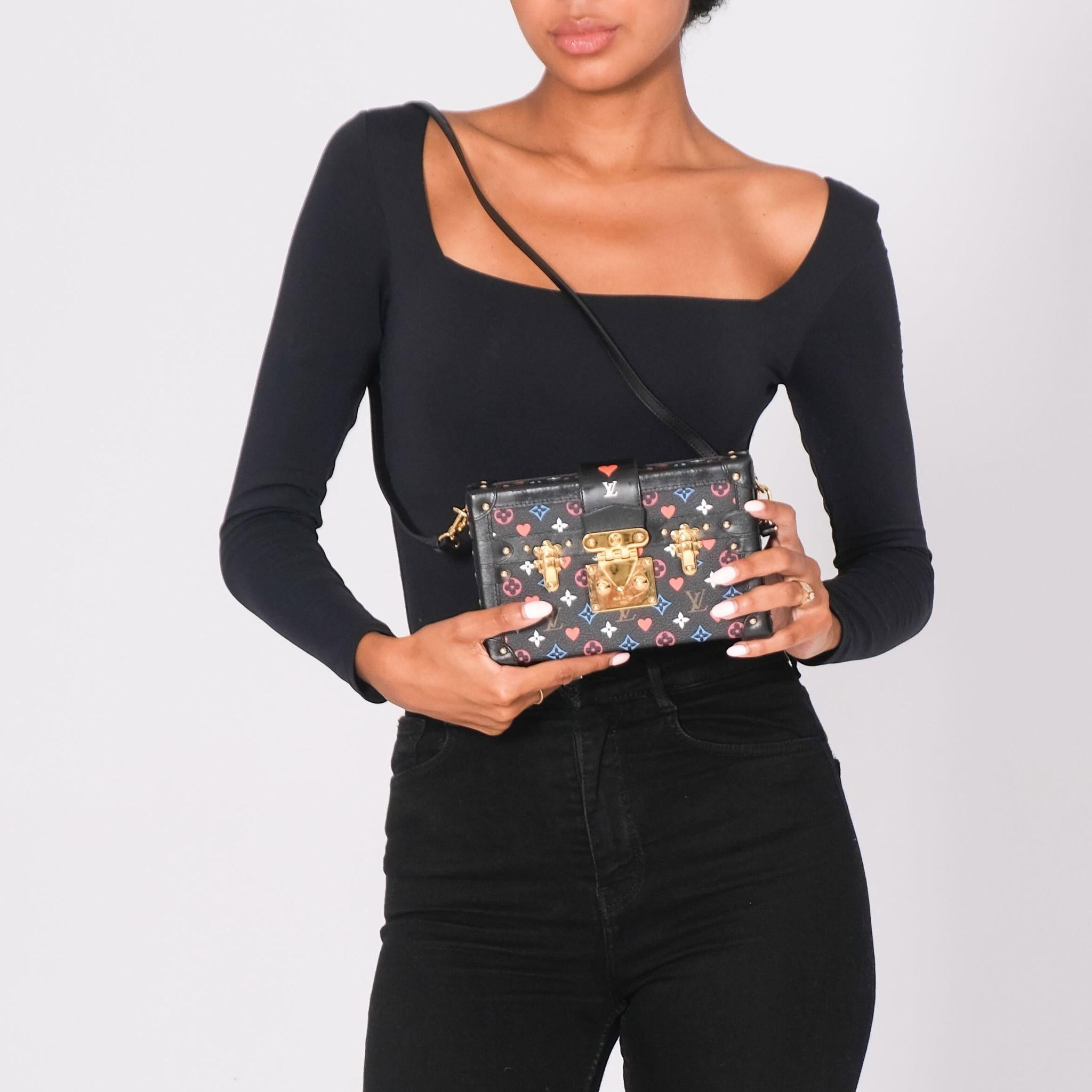 This trunk bag is made of Louis Vuitton monogram on toile canvas. The shoulder bag features an optional, adjustable black leather shoulder strap, matching leather trim, and polished black studded hardware at the joints with polished brass buckles