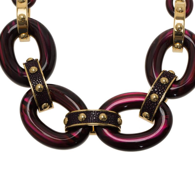 This chic piece of fashion jewelry by louis vuitton has brand detail engraved on every screw present on the necklace. Crafted in resin and gold-tone metal with leather details, it has a chain hanging at the bottom with LV logo is attached to the