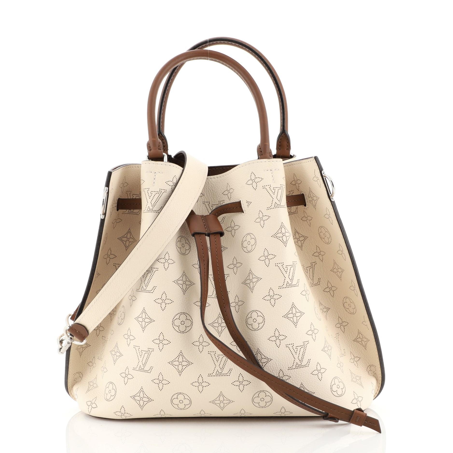 This Louis Vuitton Girolata Handbag Mahina Leather, crafted in neutral monogram mahina leather, features dual rolled leather handles, protective base studs, and silver-tone hardware. Its drawstring leather closure opens to a brown microfiber