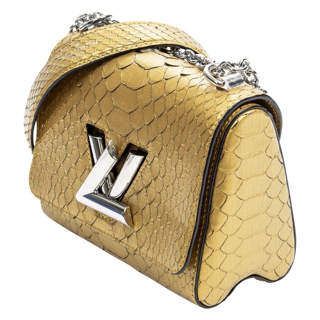 Diese limitierte Auflage der Louis Vuitton Twist PM glänzt in goldfarbenem, pythongeprägtem Leder. Der silberfarbene LV-Drehverschluss gibt den Blick auf das lederne Innere mit einem Steckfach frei, das Opulenz mit Funktionalität