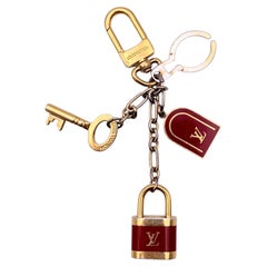 Louis Vuitton Schlüsselanhänger und Taschenanhänger „Cadenas“ aus gold- und rotfarbenem Metall