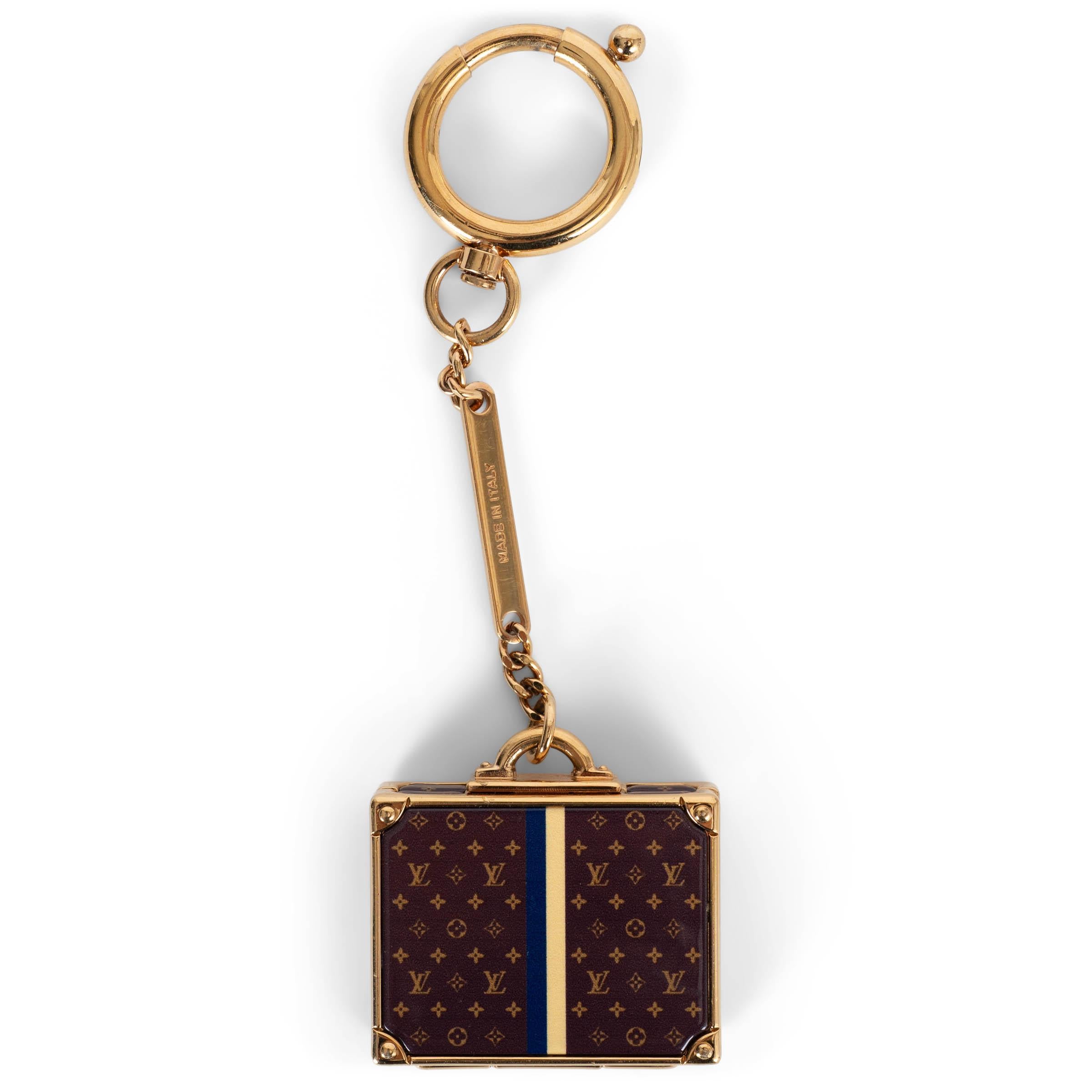 Ce porte-clés Louis Vuitton Alzer 100% authentique est réalisé en métal doré et présente un pendentif en forme de valise miniature en toile Monogram avec une bande contrastante au centre. La pièce s'ouvre pour révéler un petit miroir à l'intérieur,
