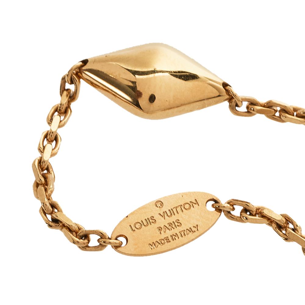 Sometimes, the simplest of designs are the most breathtaking. This minimal bracelet is by Louis Vuitton. Crafted from gold-tone metal, it is highlighted by signature charms and the famous LV logo. The bracelet fixes around the wrist with a lobster