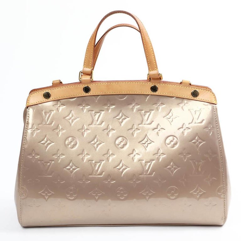 Nice trunk-shaped bag inspired by Louis Vuitton doctor's briefcases, in gold-colored patent leather. The interior is lined in fabric with 3 pockets, one of which is zipped. It is secured by a zipper.
It is in very good used condition with a pen line