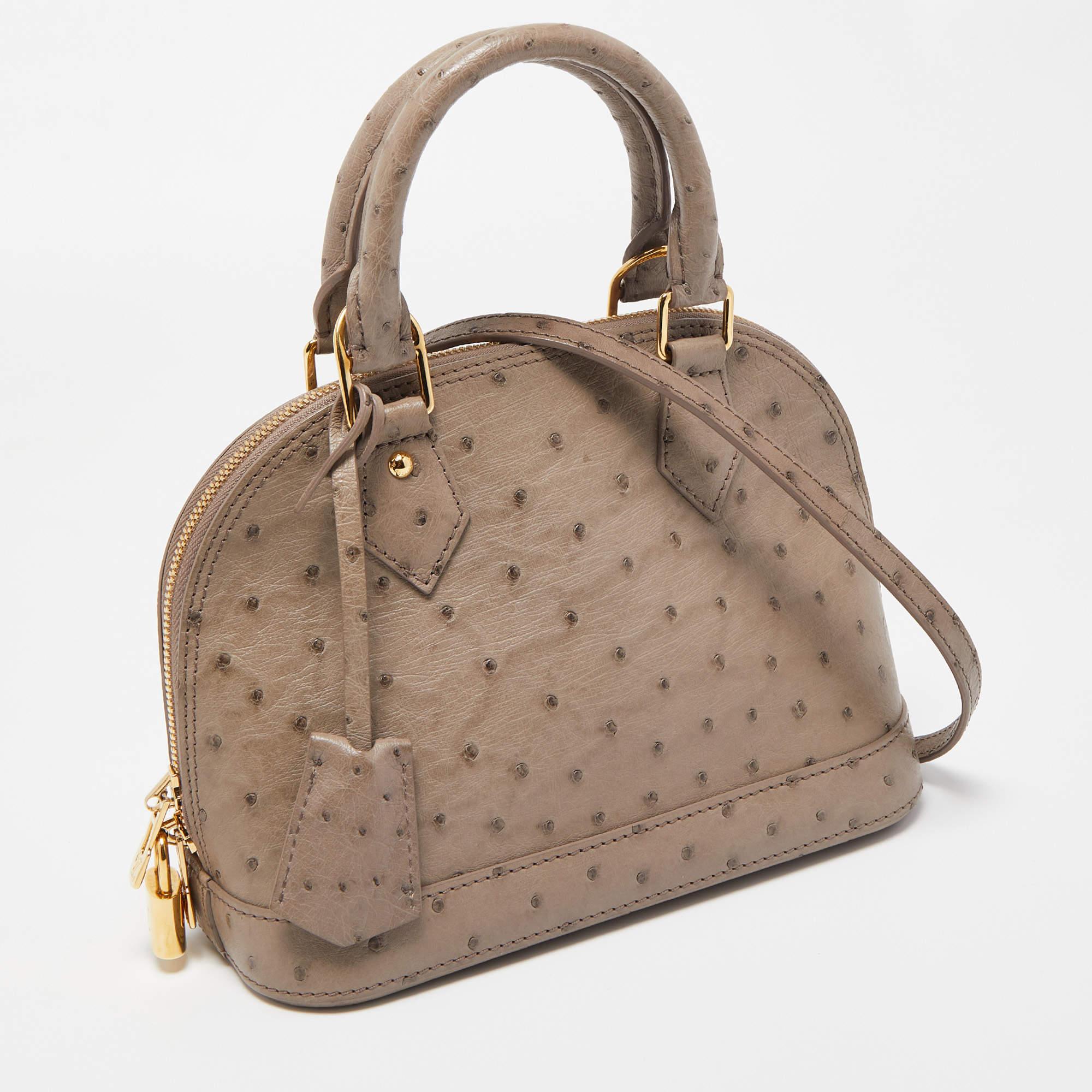 From one of the most iconic collections of Louis Vuitton, this Alma bag is imbued with exquisite craftsmanship and historic details. Constructed from Ostrich leather, it displays dual top handles, a shoulder strap, and gold-tone hardware. The