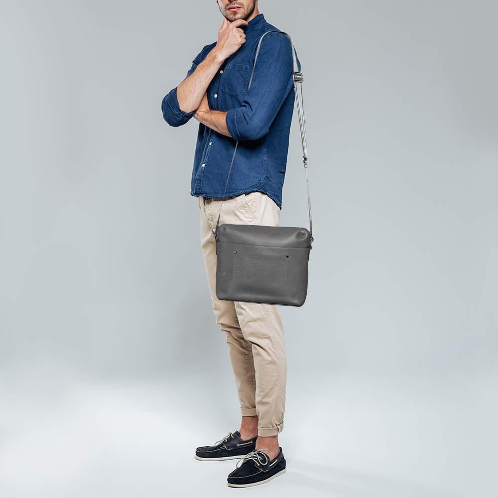 Smart and functional, this Grigori messenger bag from Louis Vuitton is a must-have. It has been crafted from grey Taiga leather and is equipped with an adjustable shoulder strap. The zip-top closure opens to a spacious canvas-lined