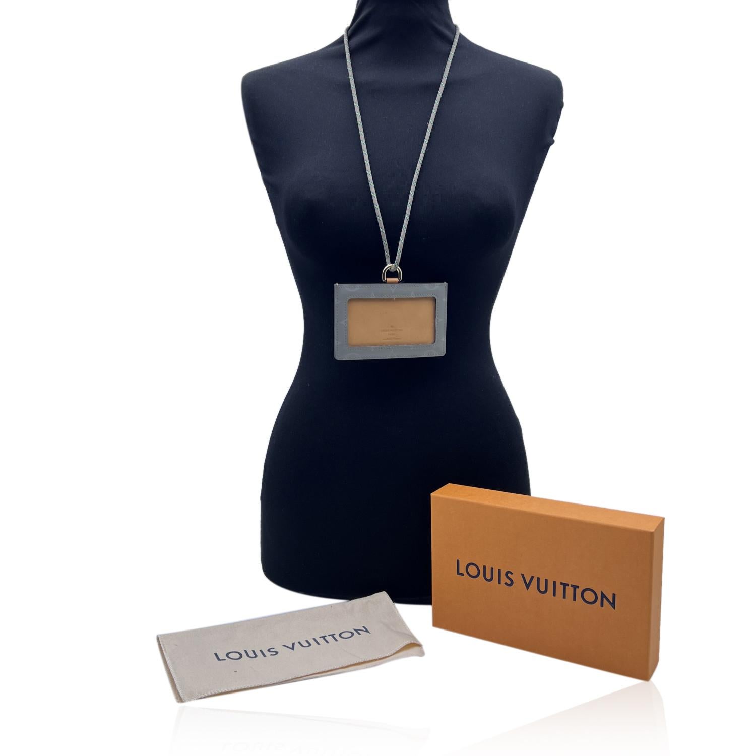 Louis Vuitton 'Cosmos' badge and card holder made of Titanium grey canvas and beige leather. The model is equipped with 2 compartments in which to store your documents with order and safety. It features a removable cord to wear around the neck.
