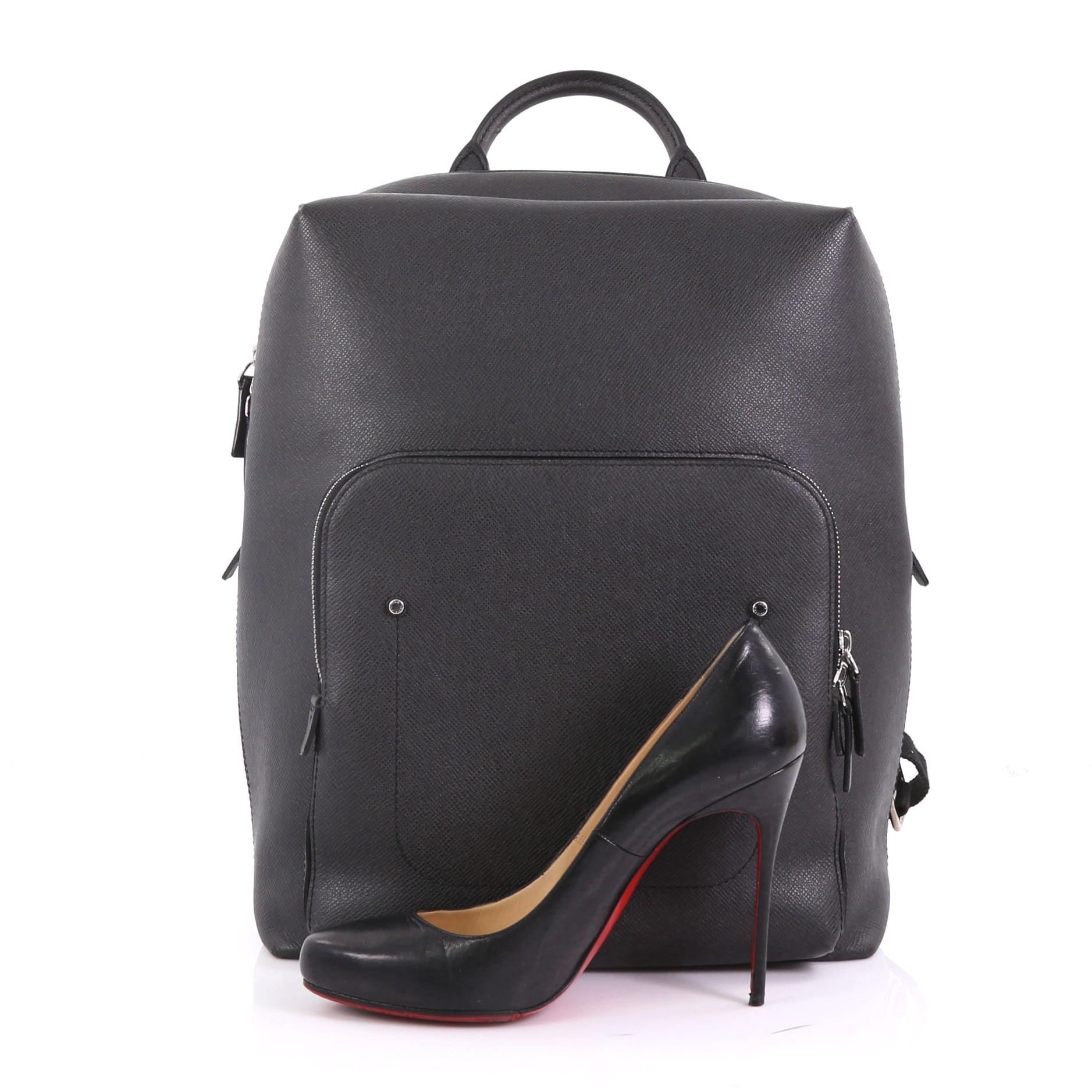 This Louis Vuitton Grigori Backpack Taiga Leather, crafted from black taiga leather, features rolled top handle, adjustable backpack straps, front zip pocket, and silver-tone hardware. Its top zip closure opens to a black fabric interior with zip