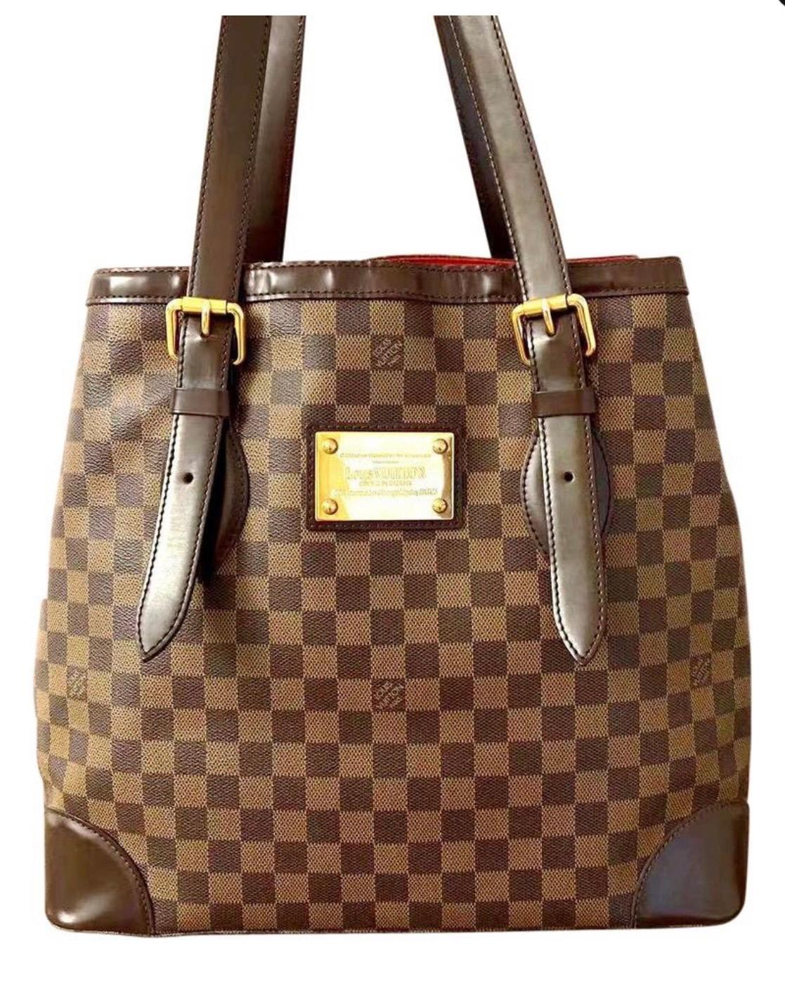 Structured Hampstead tote rendered in Louis Vuitton's signature Damier Ebene checked coated canvas, trimmed with tonal leather and accented with gold-tone brass hardware.

About LV Damier: The Damier, which translates to 
